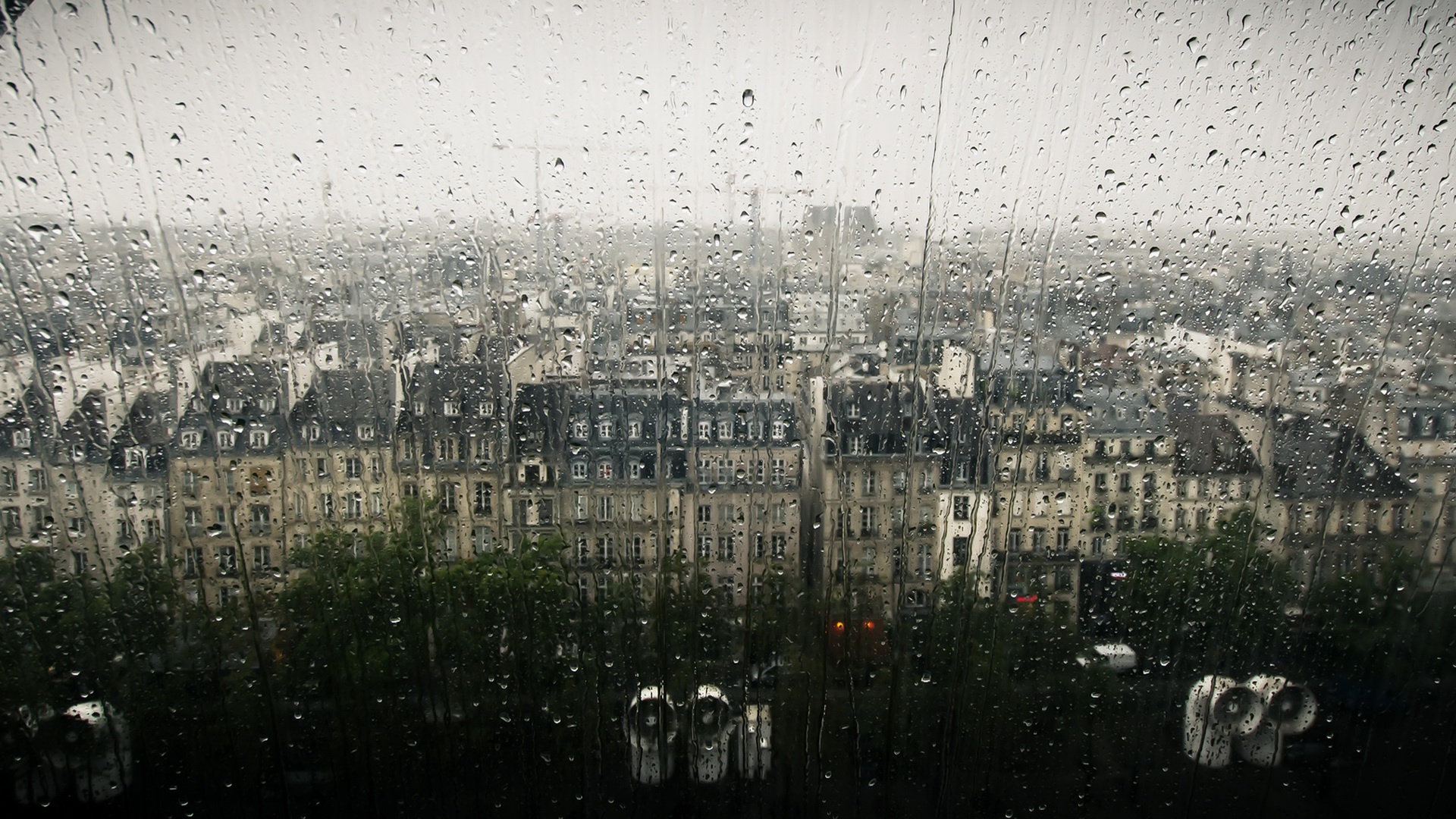 Rainy cityscape viewed through a window HD Wallpaper