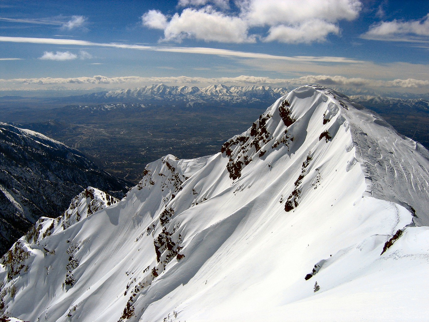 Snow-covered mountain peak overlooking a valley HD Wallpaper