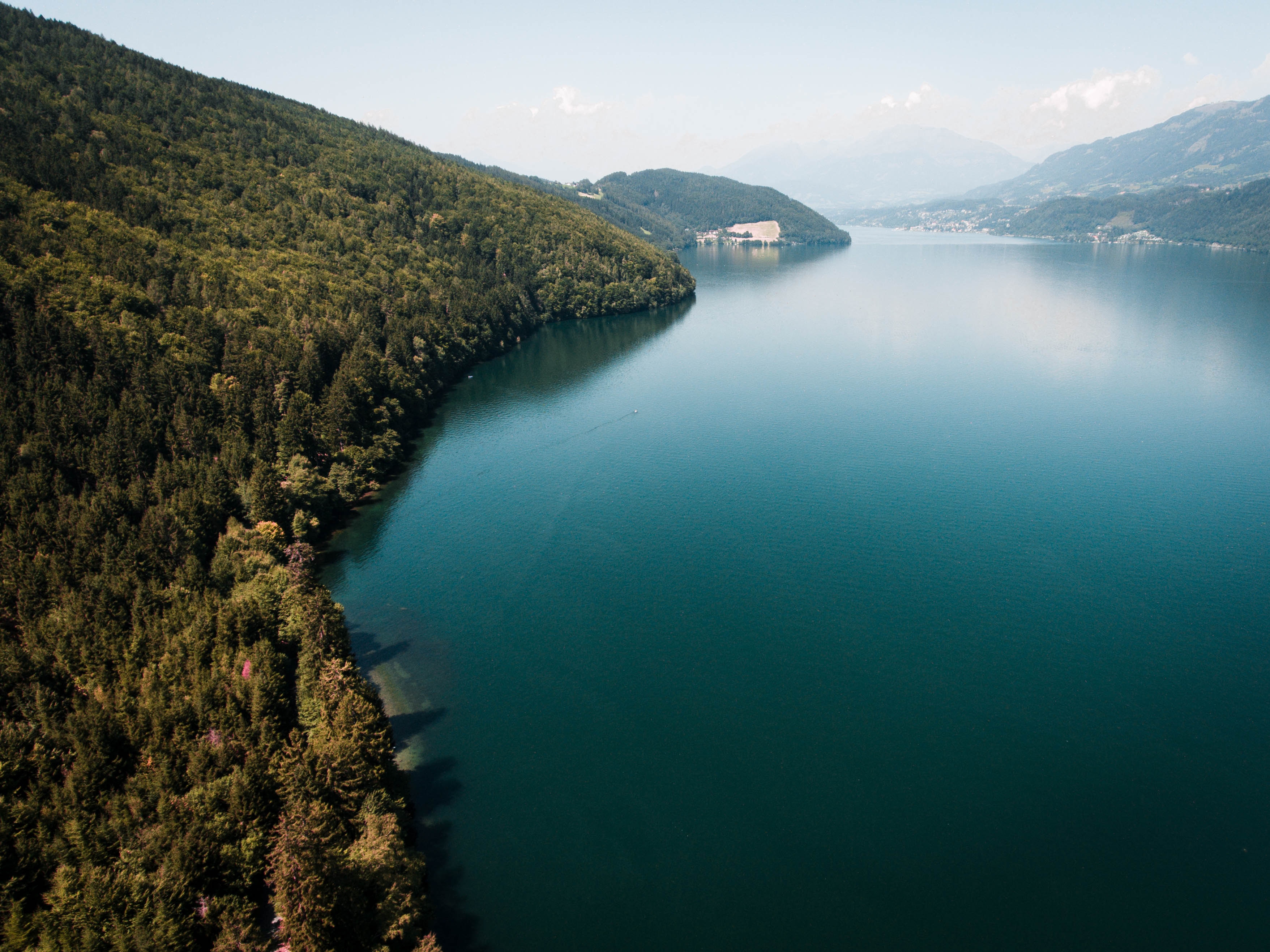 Forest-covered mountains meet a tranquil lake HD Wallpaper