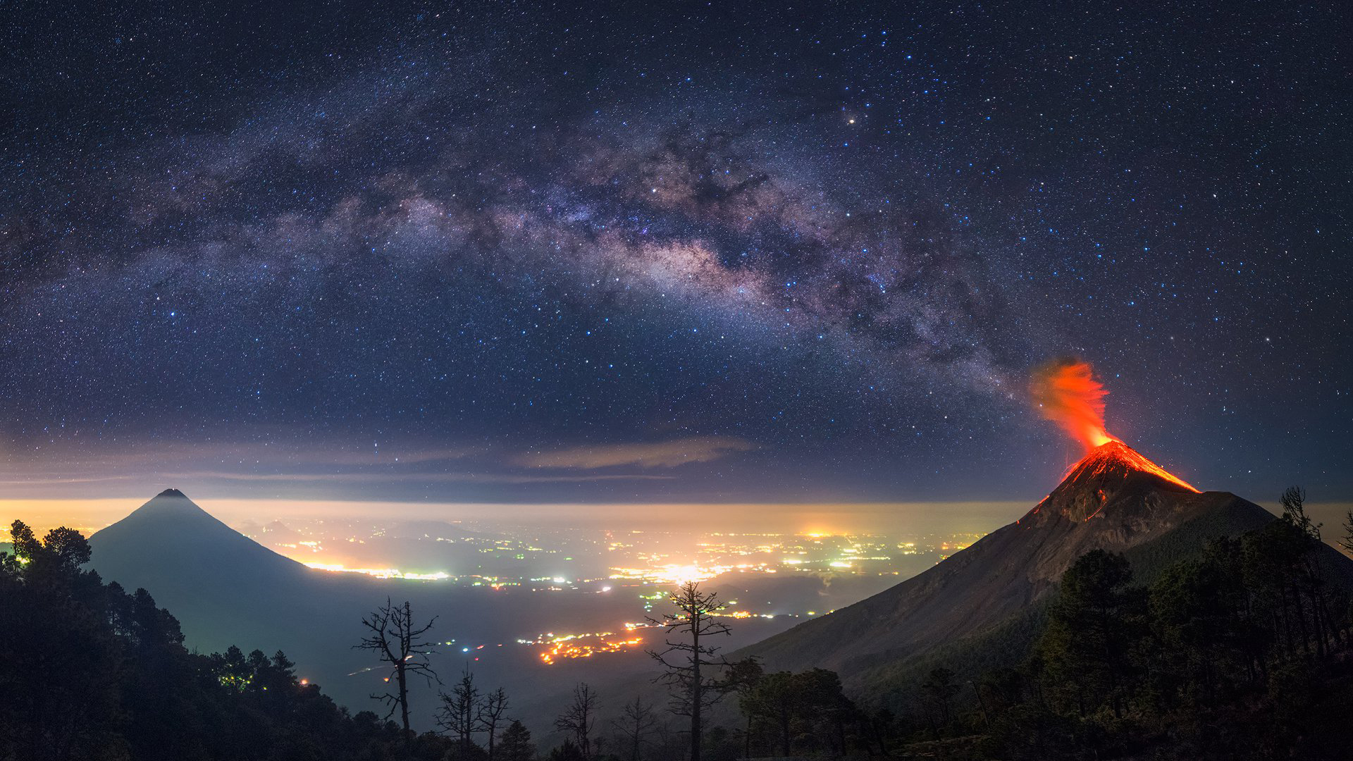 Volcano eruption under the Milky Way over a cityscape HD Wallpaper