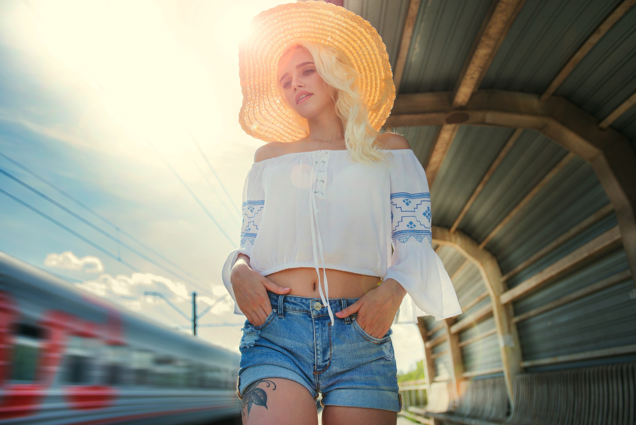 Woman in straw hat and jean shorts at train station HD Wallpaper