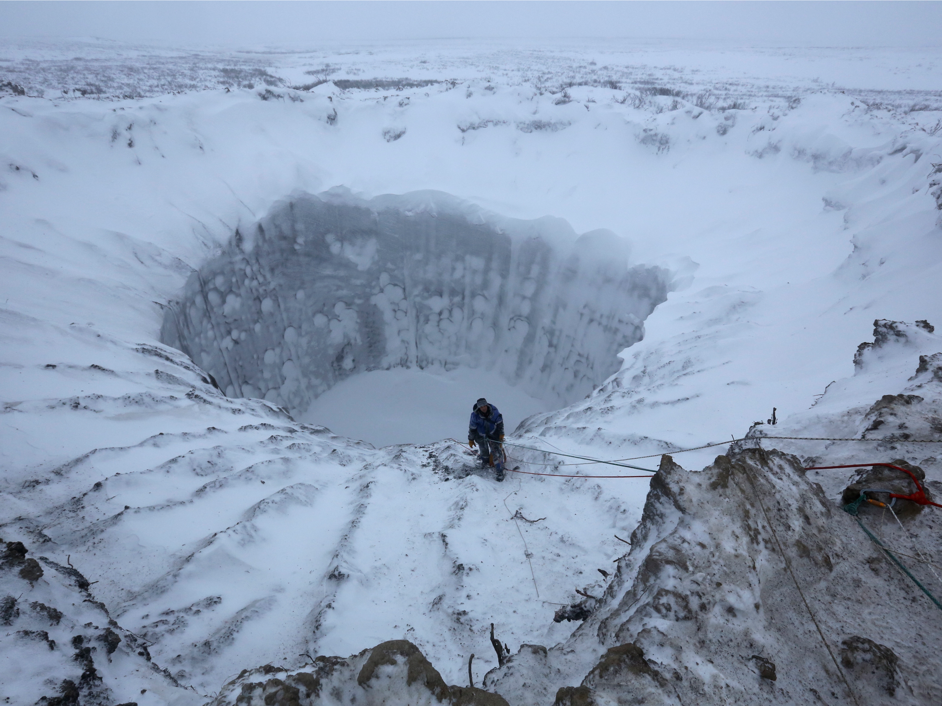 Man rappels into a massive icy crater in Siberia HD Wallpaper