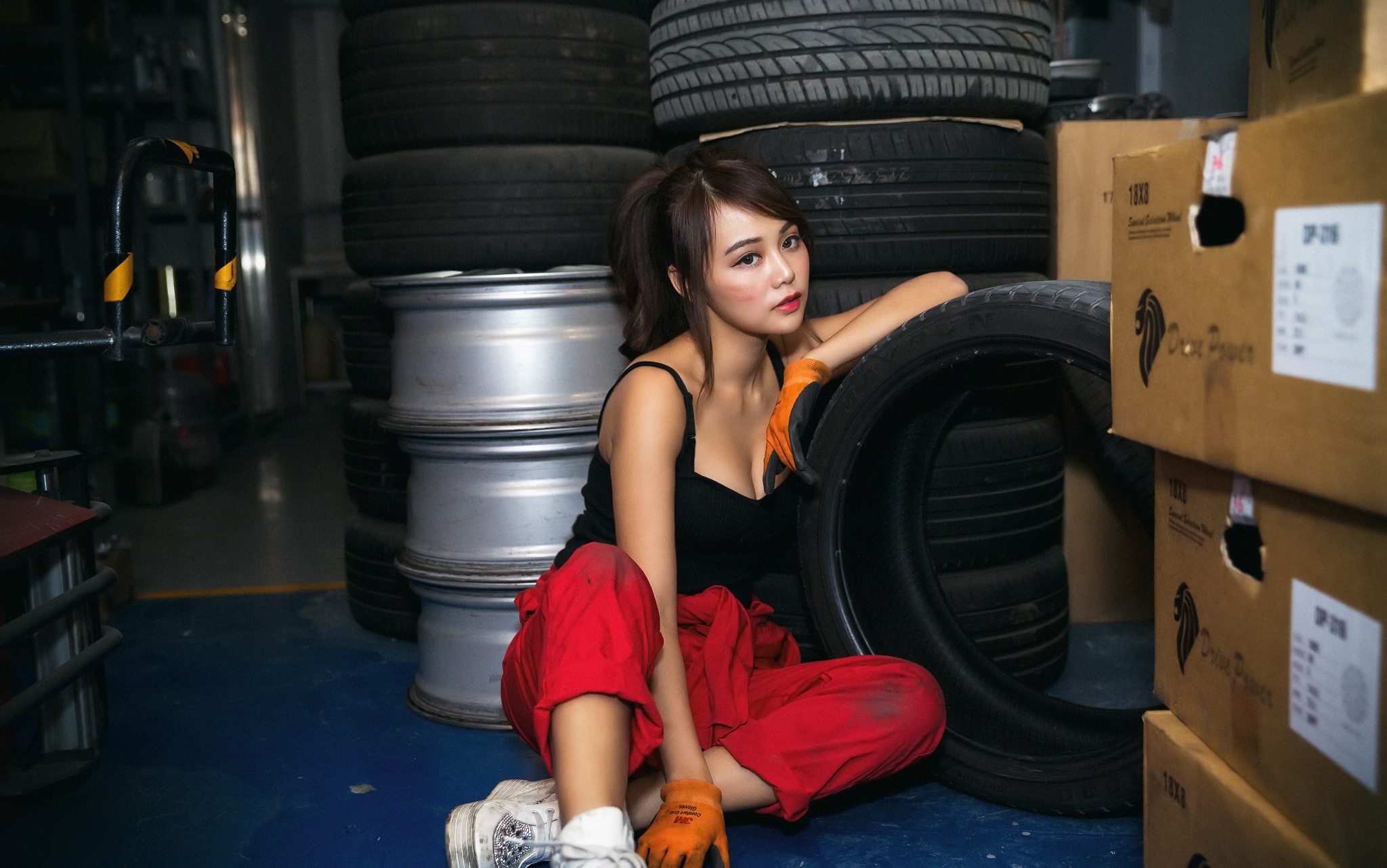 Woman in red overalls with tires and boxes HD Wallpaper