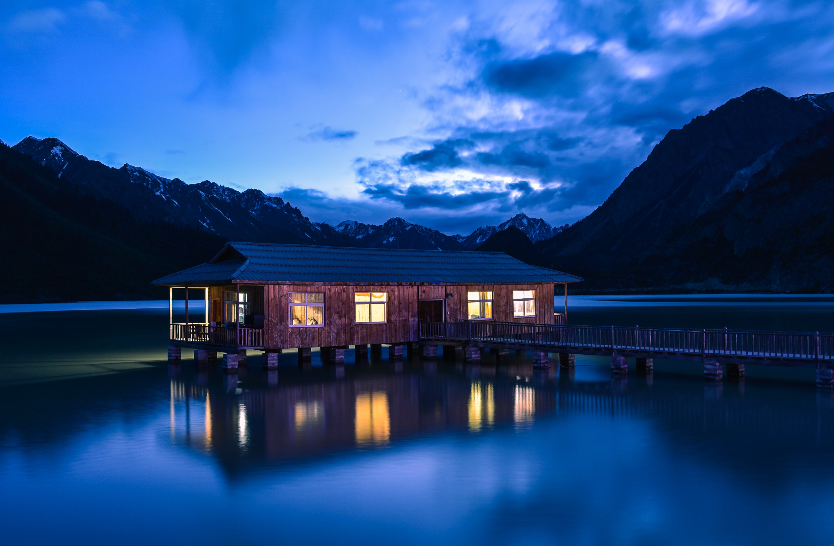 Wooden house on stilts on a lake at dusk HD Wallpaper