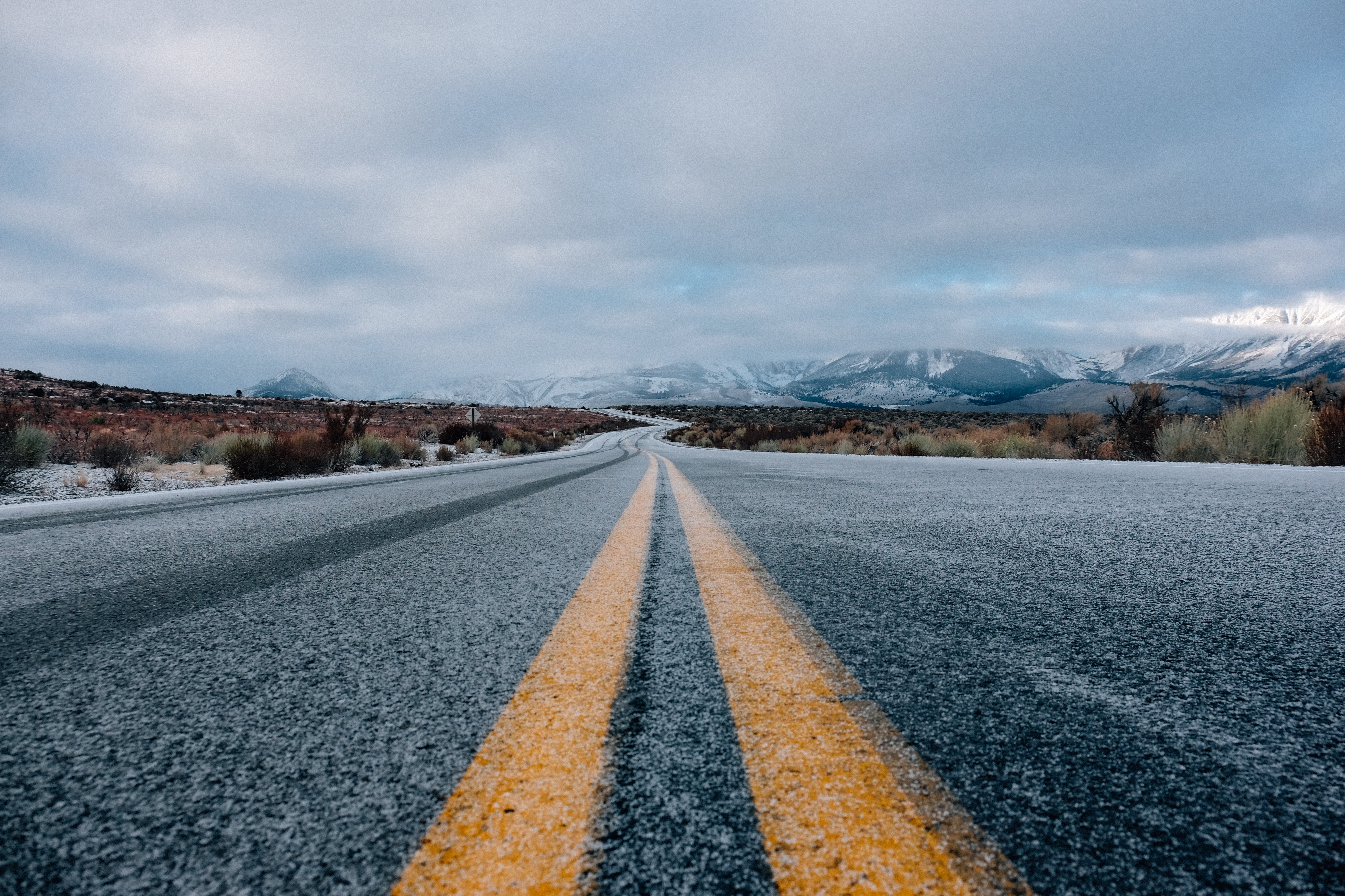 Empty road with yellow lines in a snowy landscape HD Wallpaper