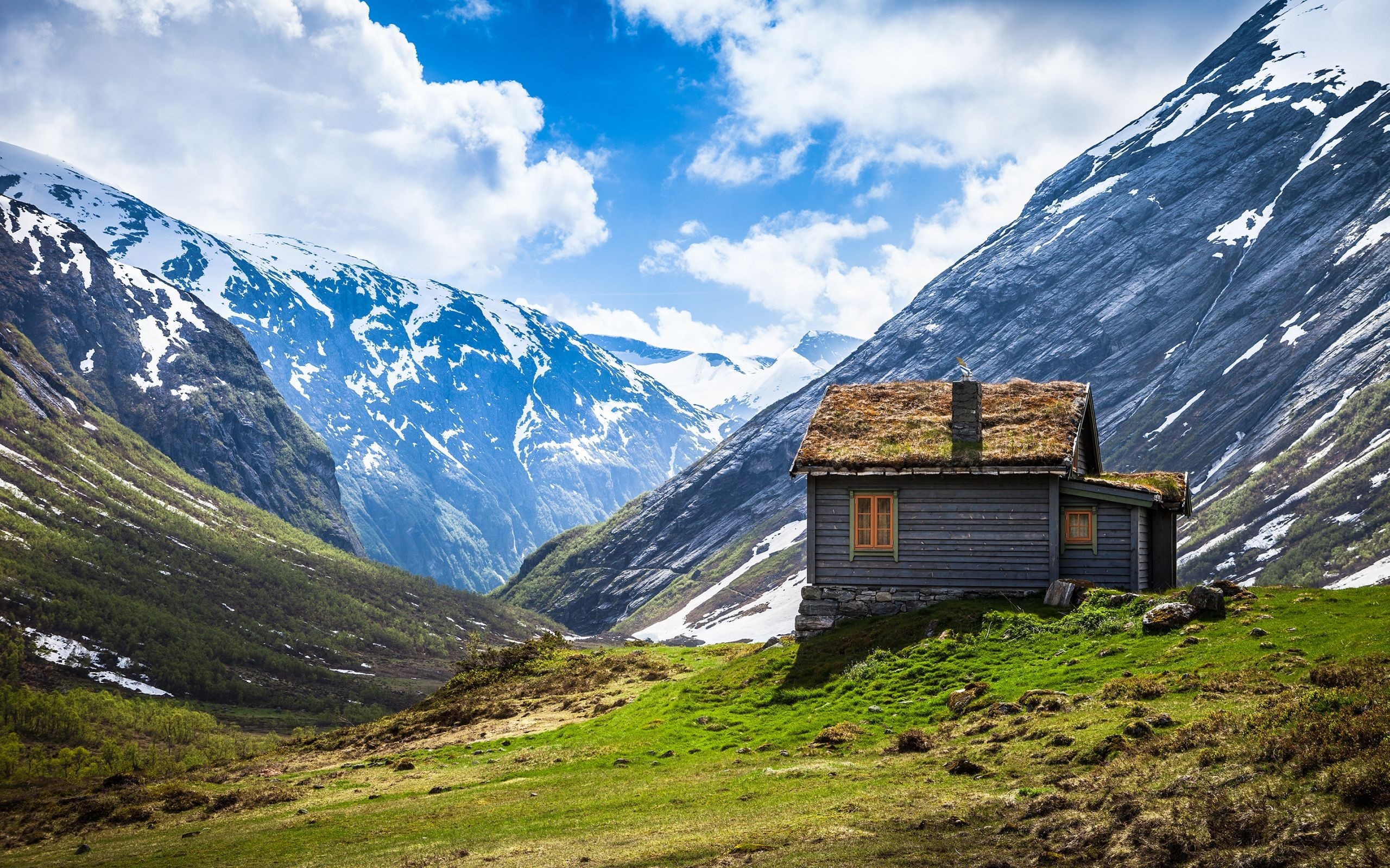 Wooden cabin in a mountain valley with snow-capped peaks HD Wallpaper