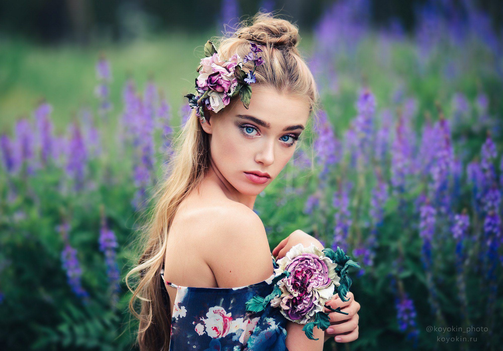 Woman with flowers in hair and on arm in field HD Wallpaper