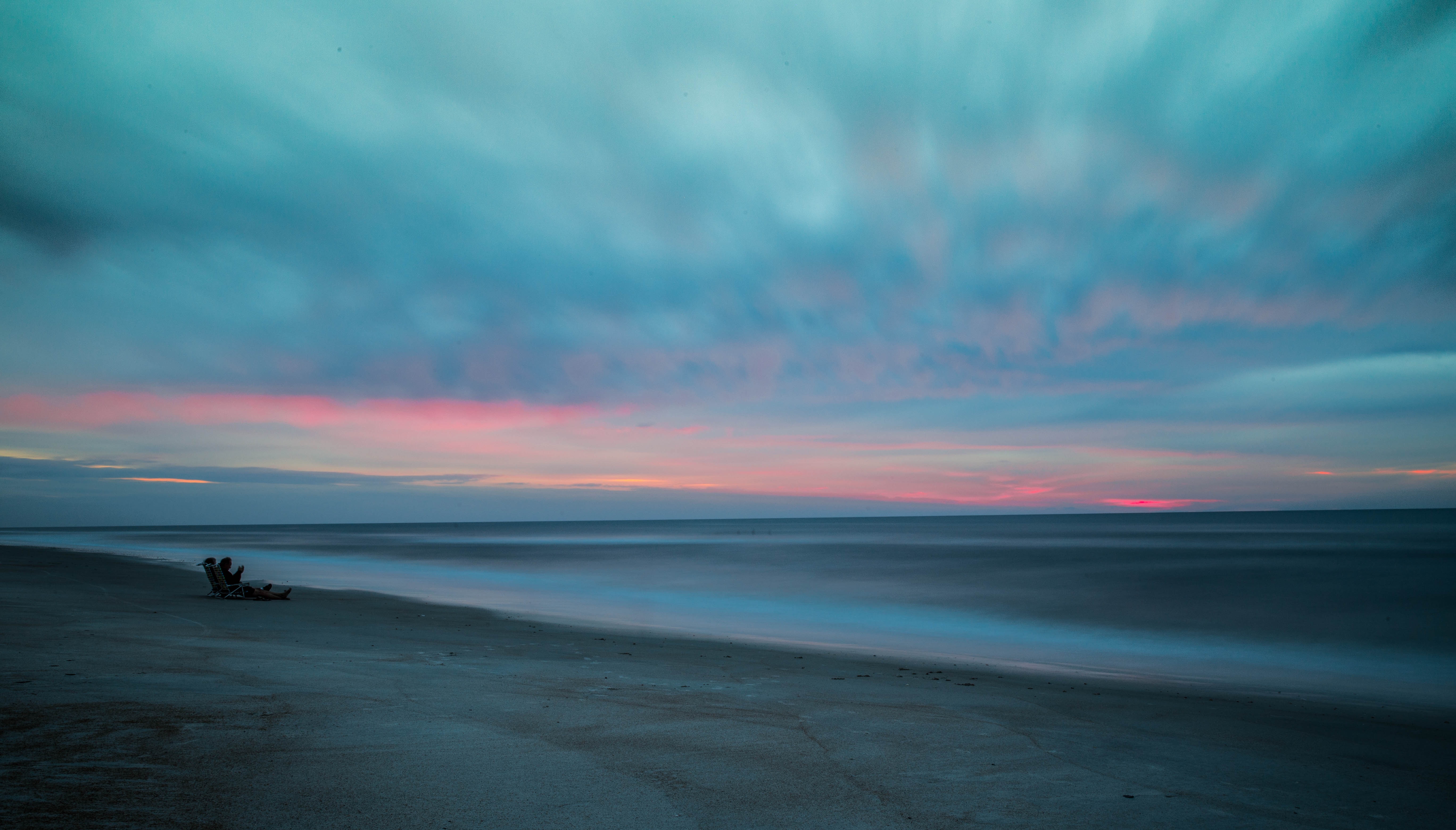 Person sitting on a beach chair at sunset HD Wallpaper