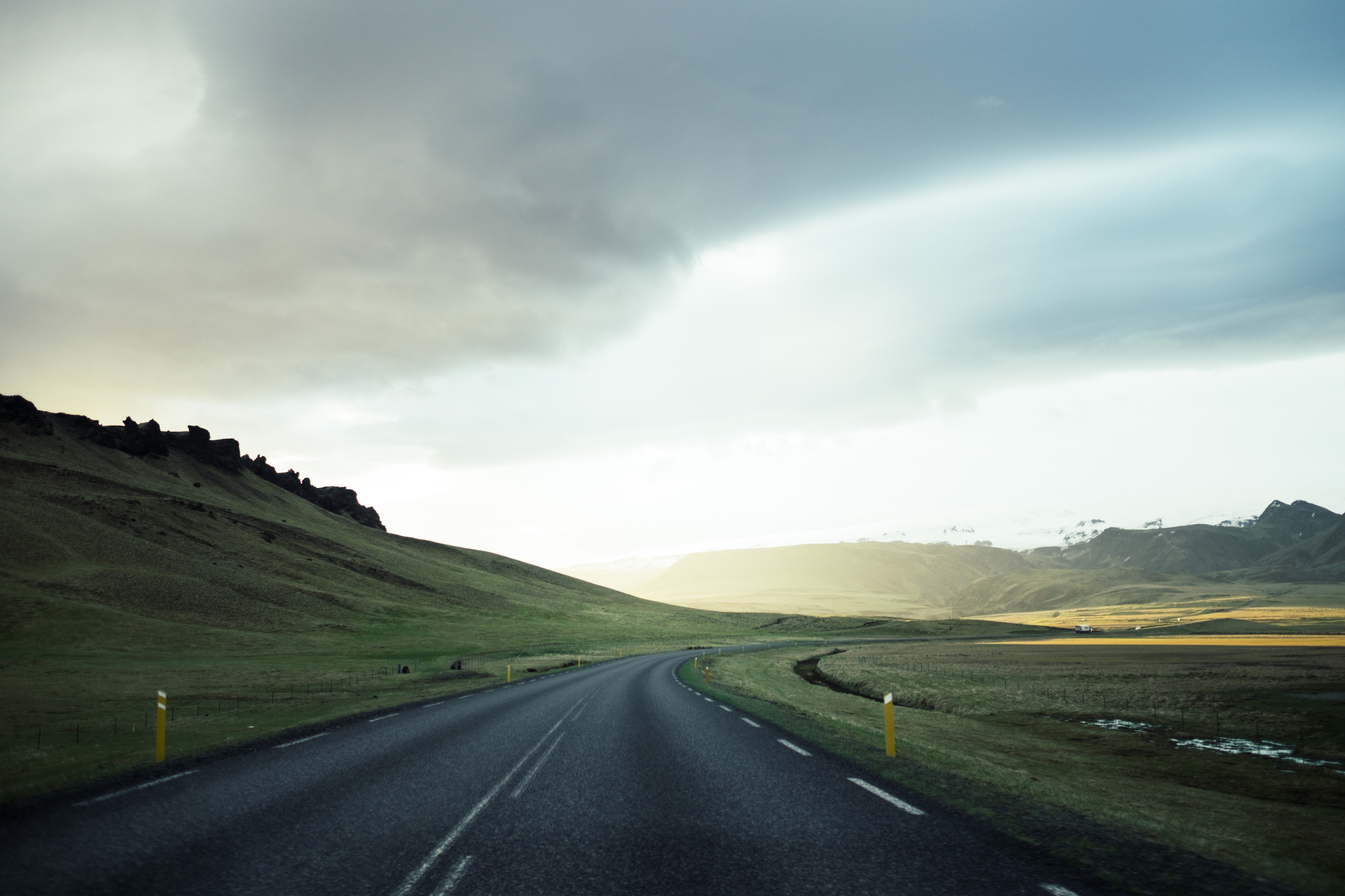 Road through a green landscape under a cloudy sky HD Wallpaper