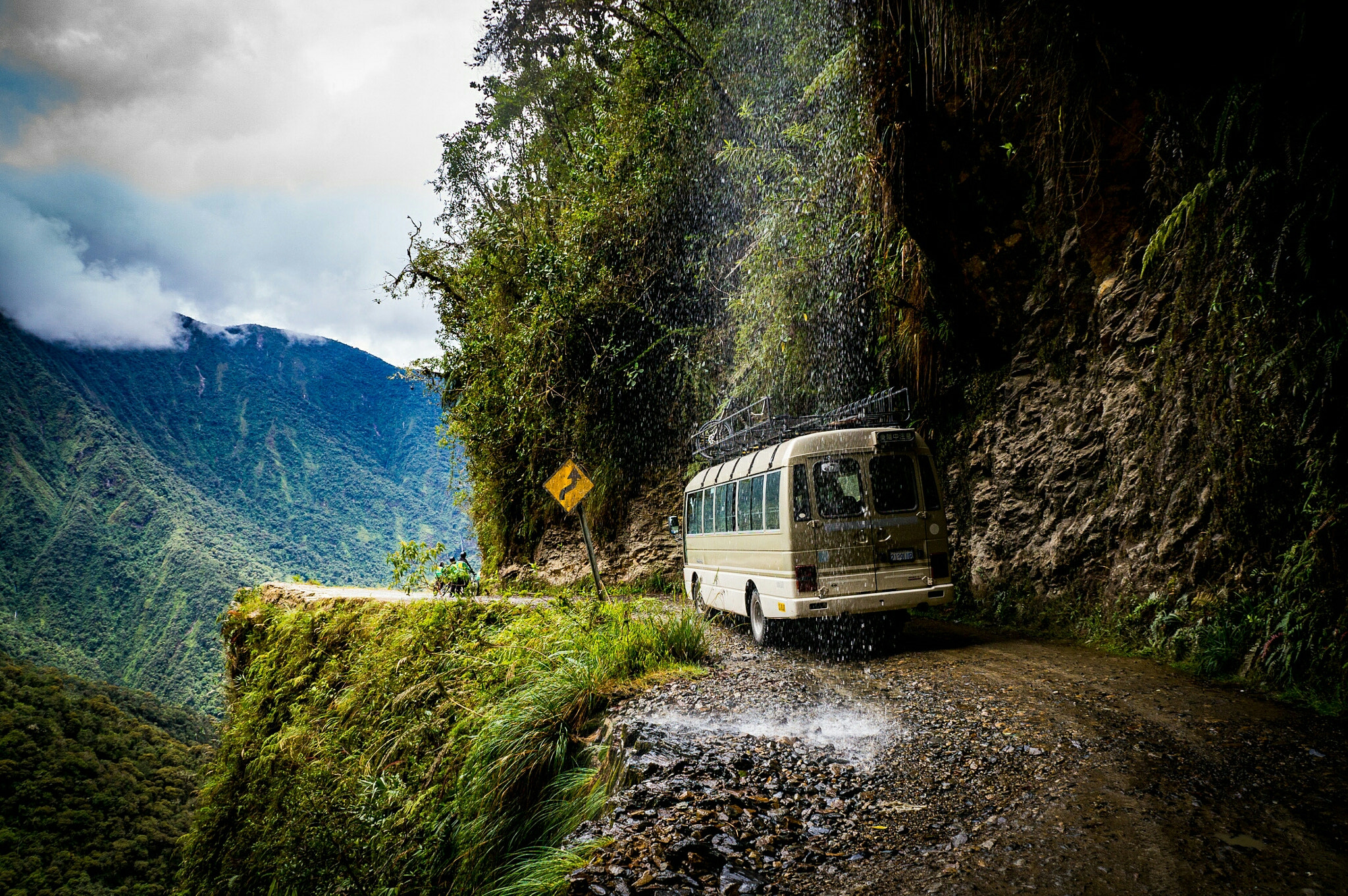 Bus on a narrow mountain road with a steep drop HD Wallpaper