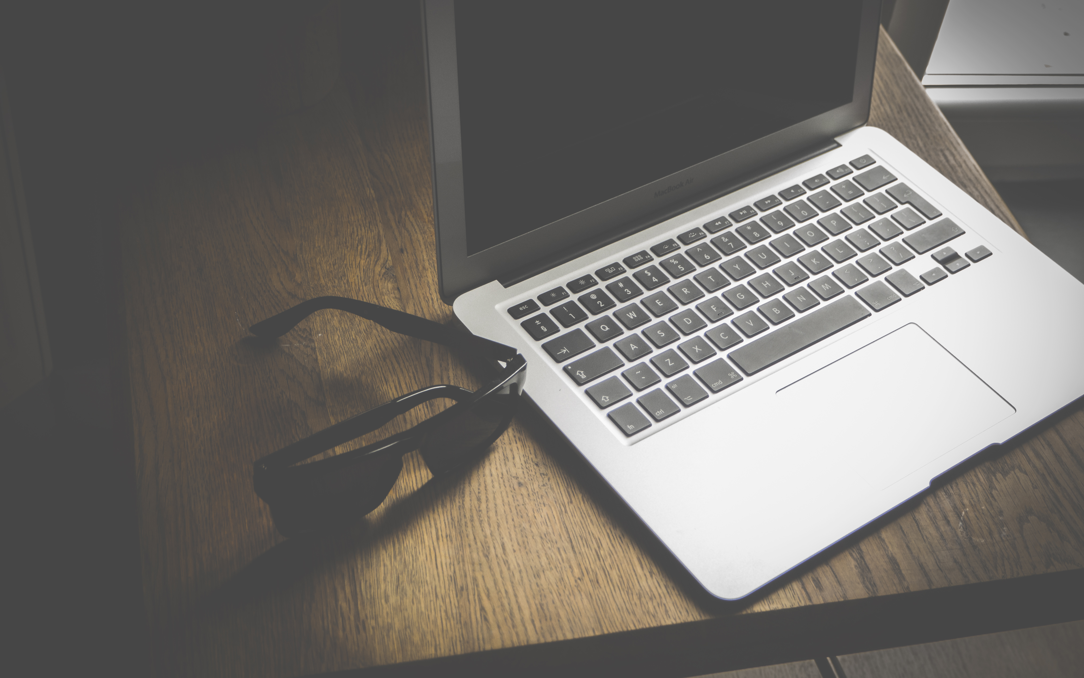 MacBook laptop and glasses on a wooden table HD Wallpaper