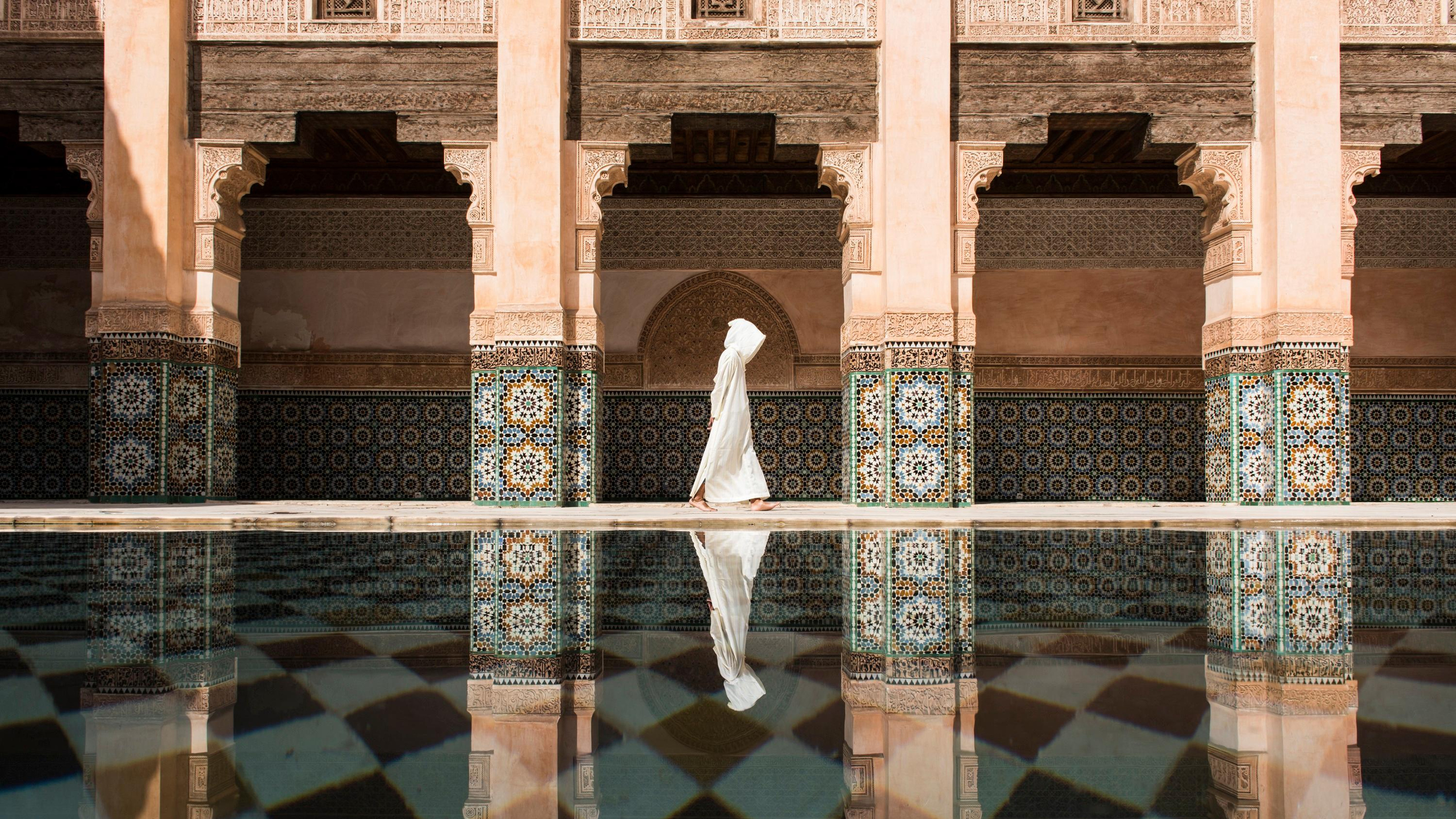 Person in white robe walking by a pool in Marrakesh HD Wallpaper