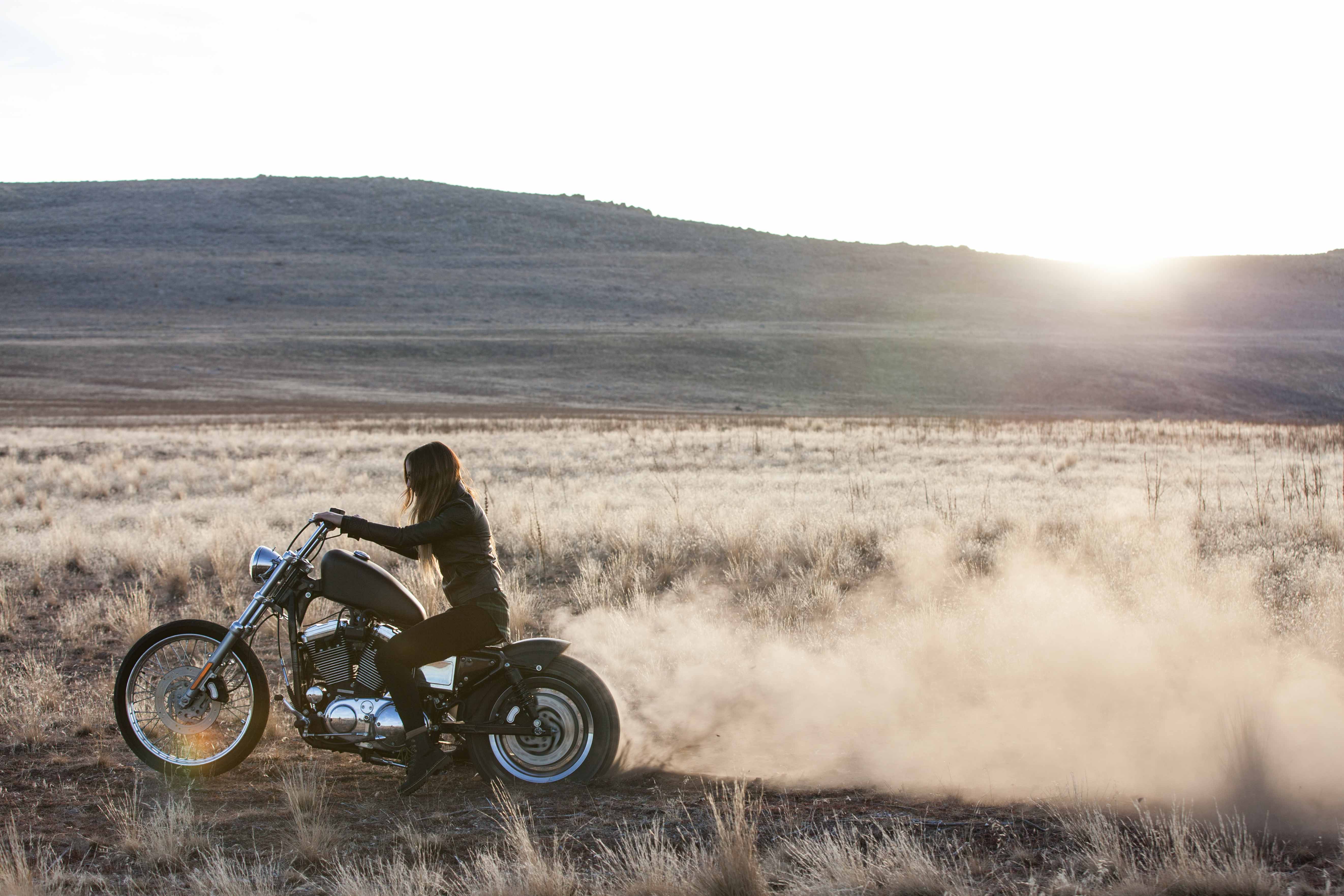 Woman riding a motorcycle in a dry landscape HD Wallpaper