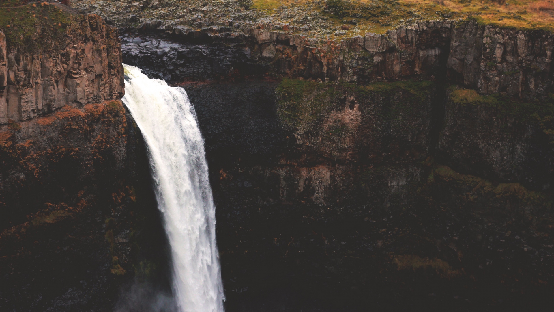 Waterfall cascading over a rocky cliff face HD Wallpaper