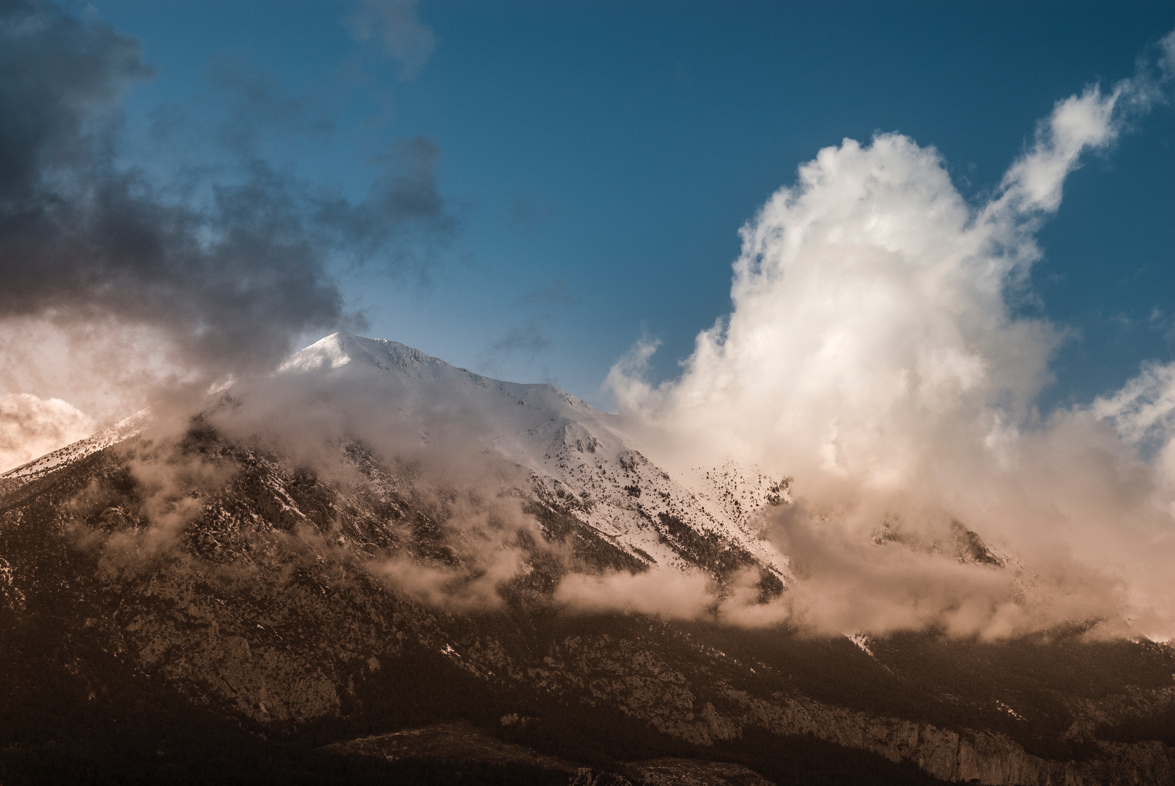 Snow-capped mountain peak shrouded in clouds HD Wallpaper