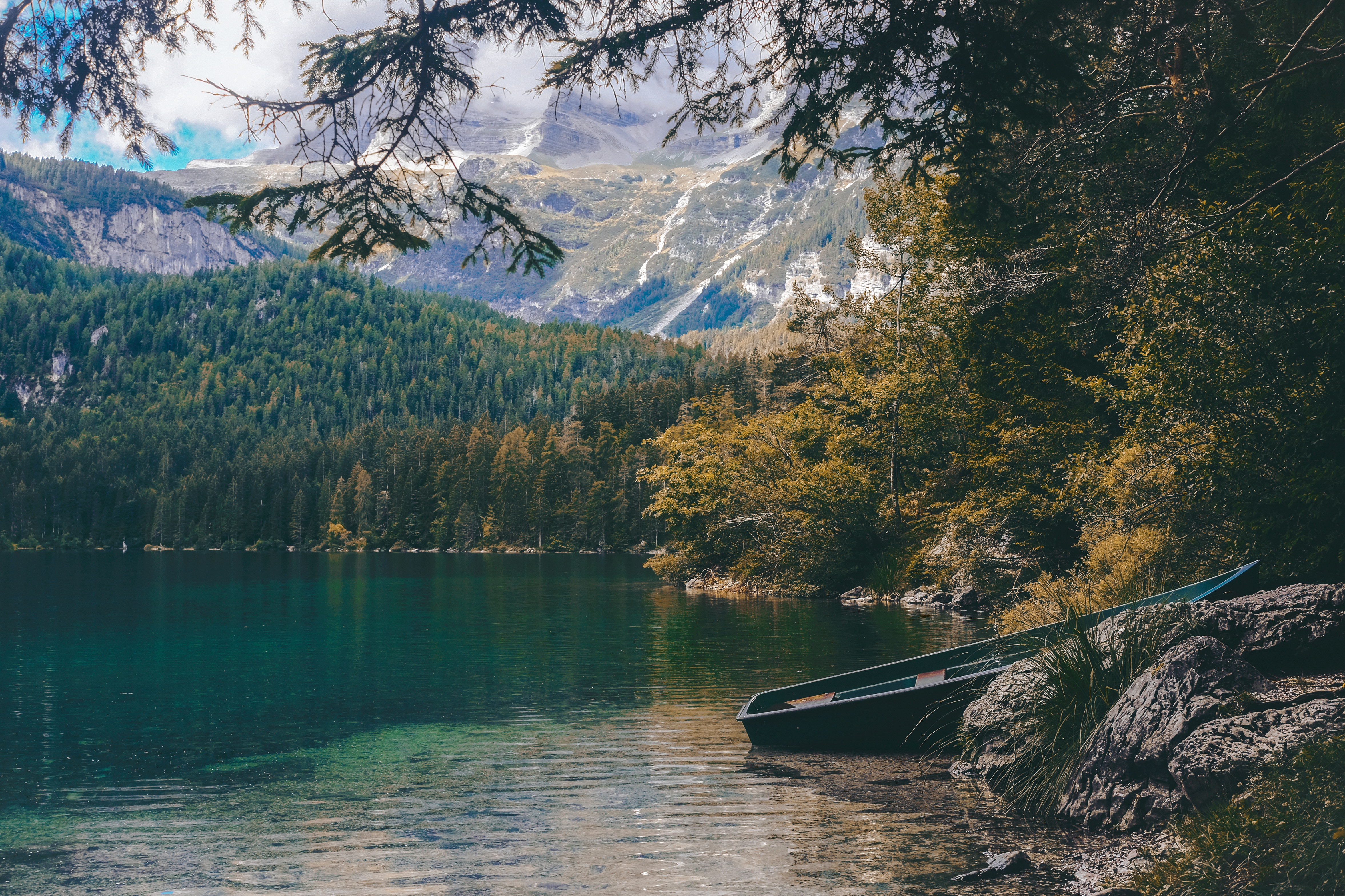 Boat on a rocky shore of a lake with mountains HD Wallpaper