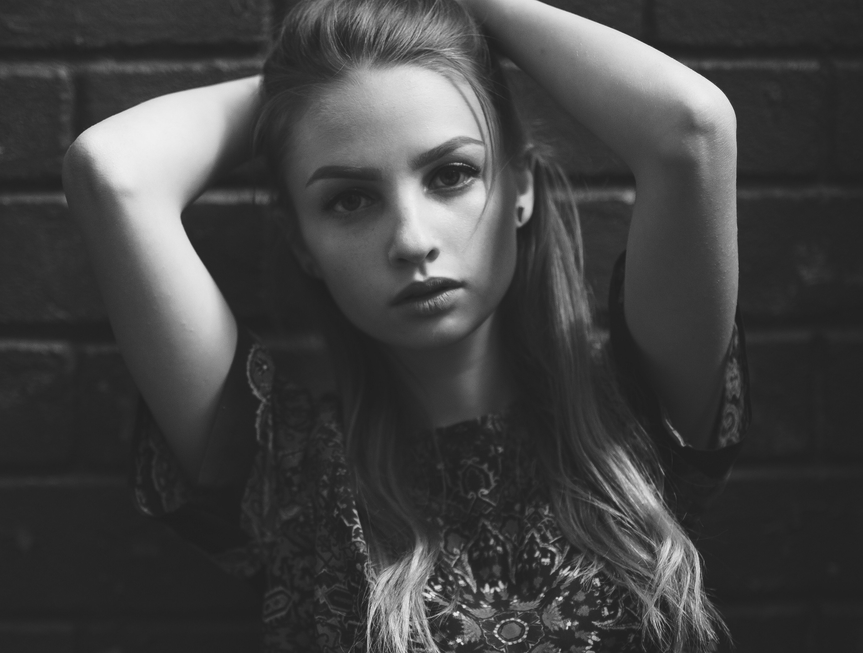 Monochrome portrait of a woman with hands behind her head HD Wallpaper