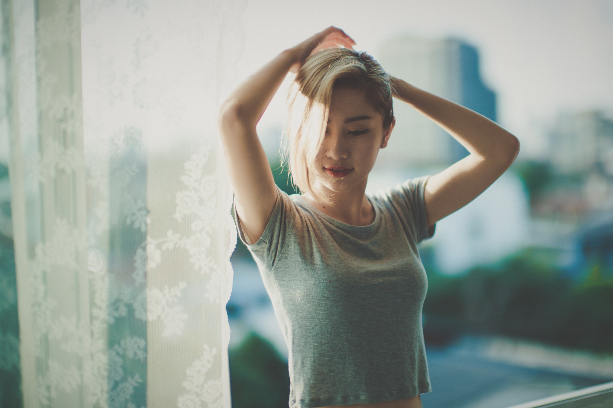 Asian woman with blonde hair by a window HD Wallpaper