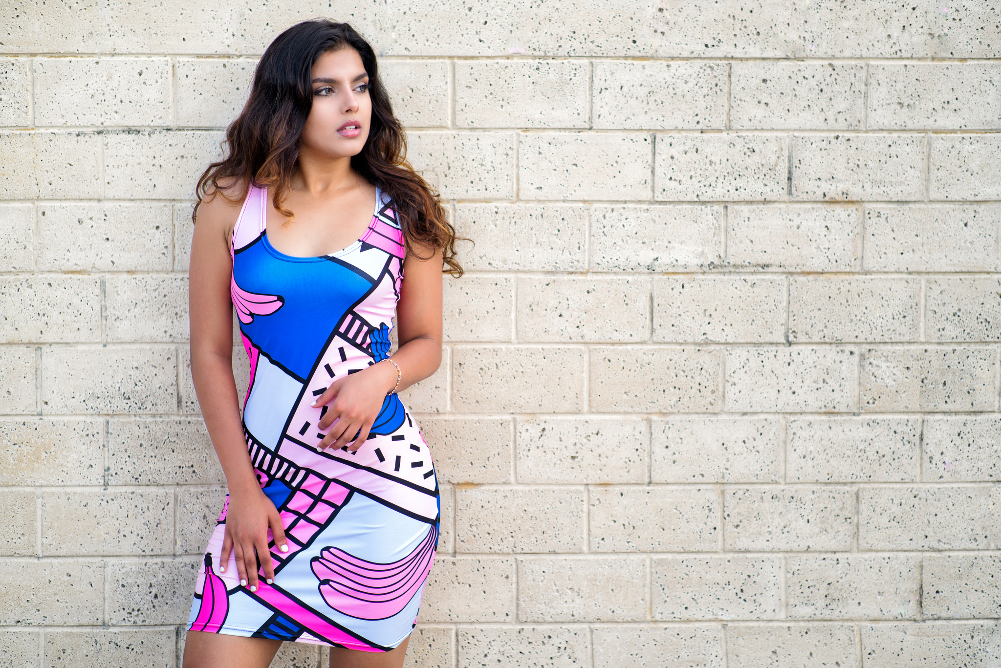Woman in a colorful dress leaning against a brick wall HD Wallpaper