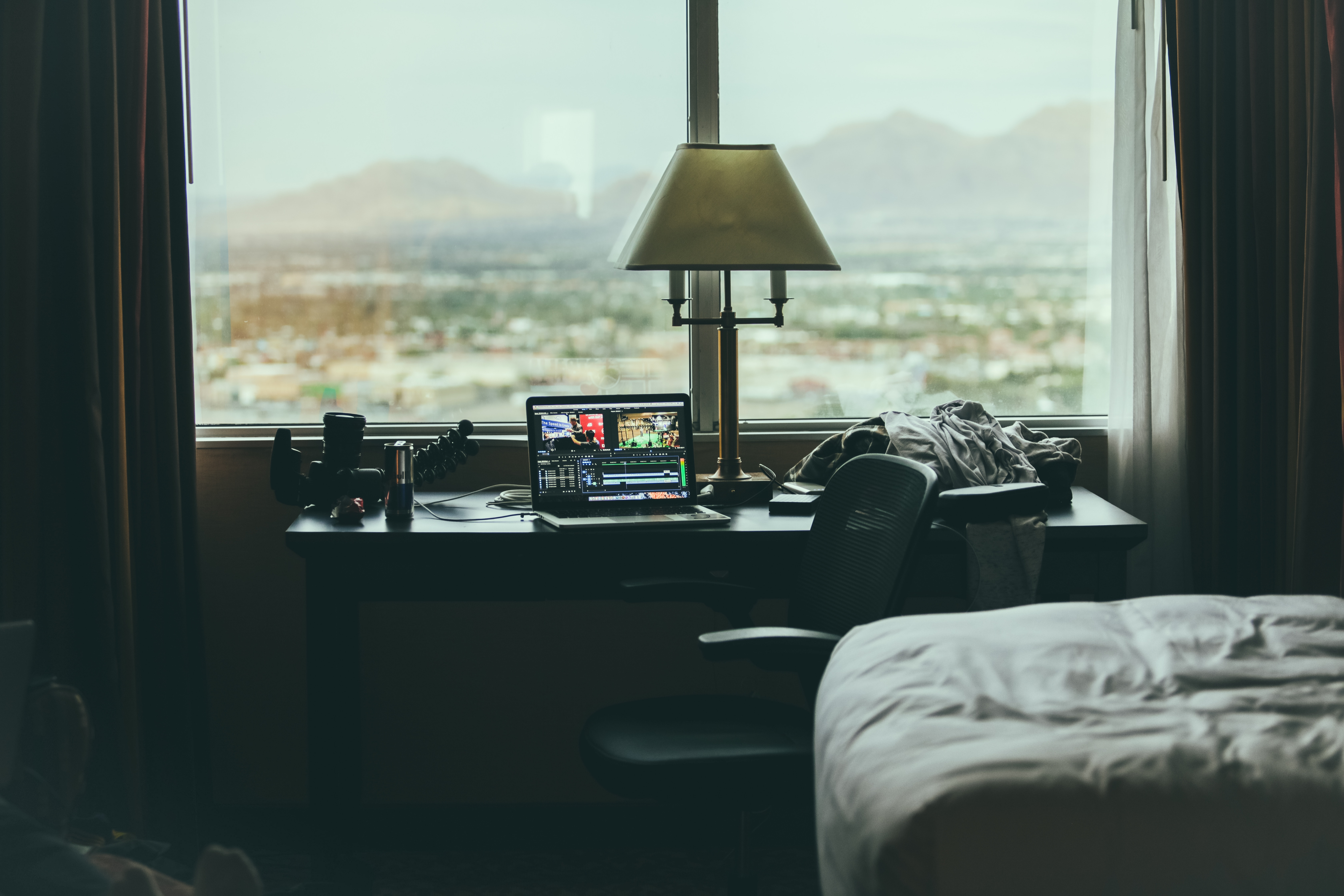 Desk with laptop and camera by the window HD Wallpaper