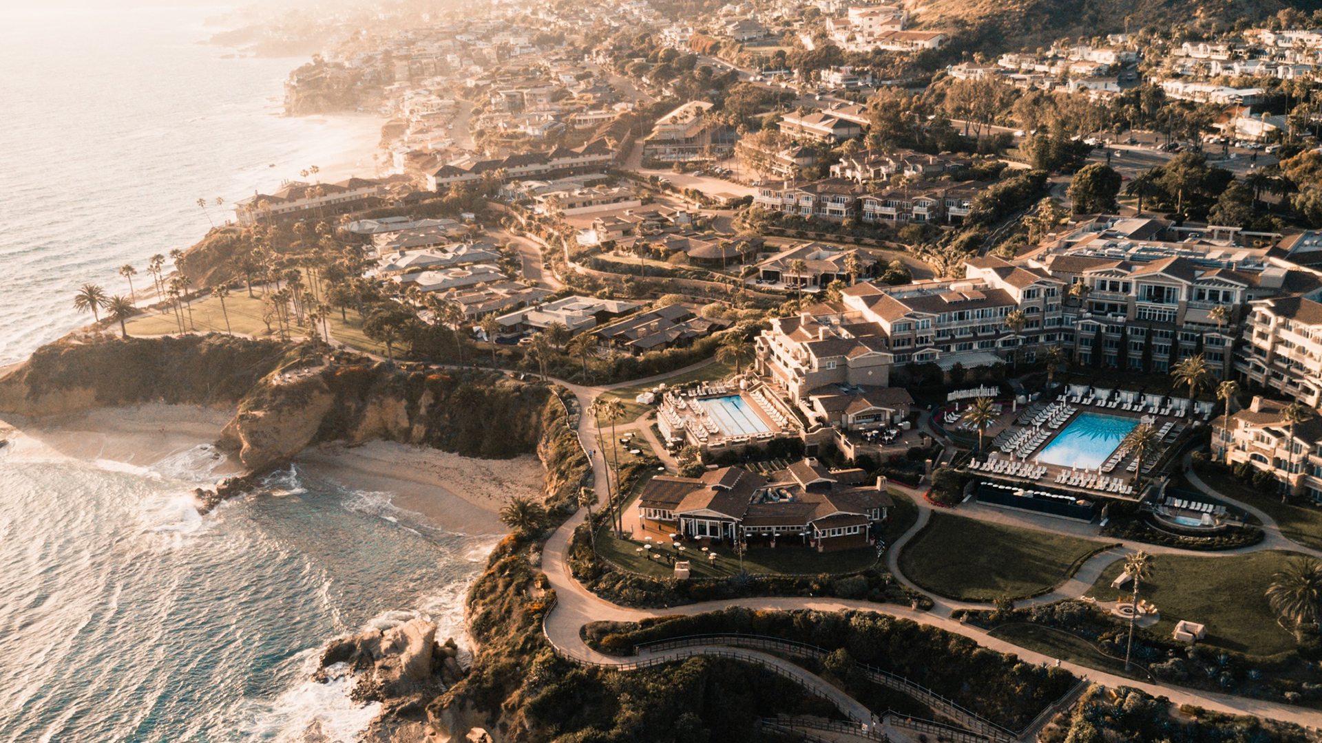 Aerial view of a coastal resort with swimming pools and ocean HD Wallpaper