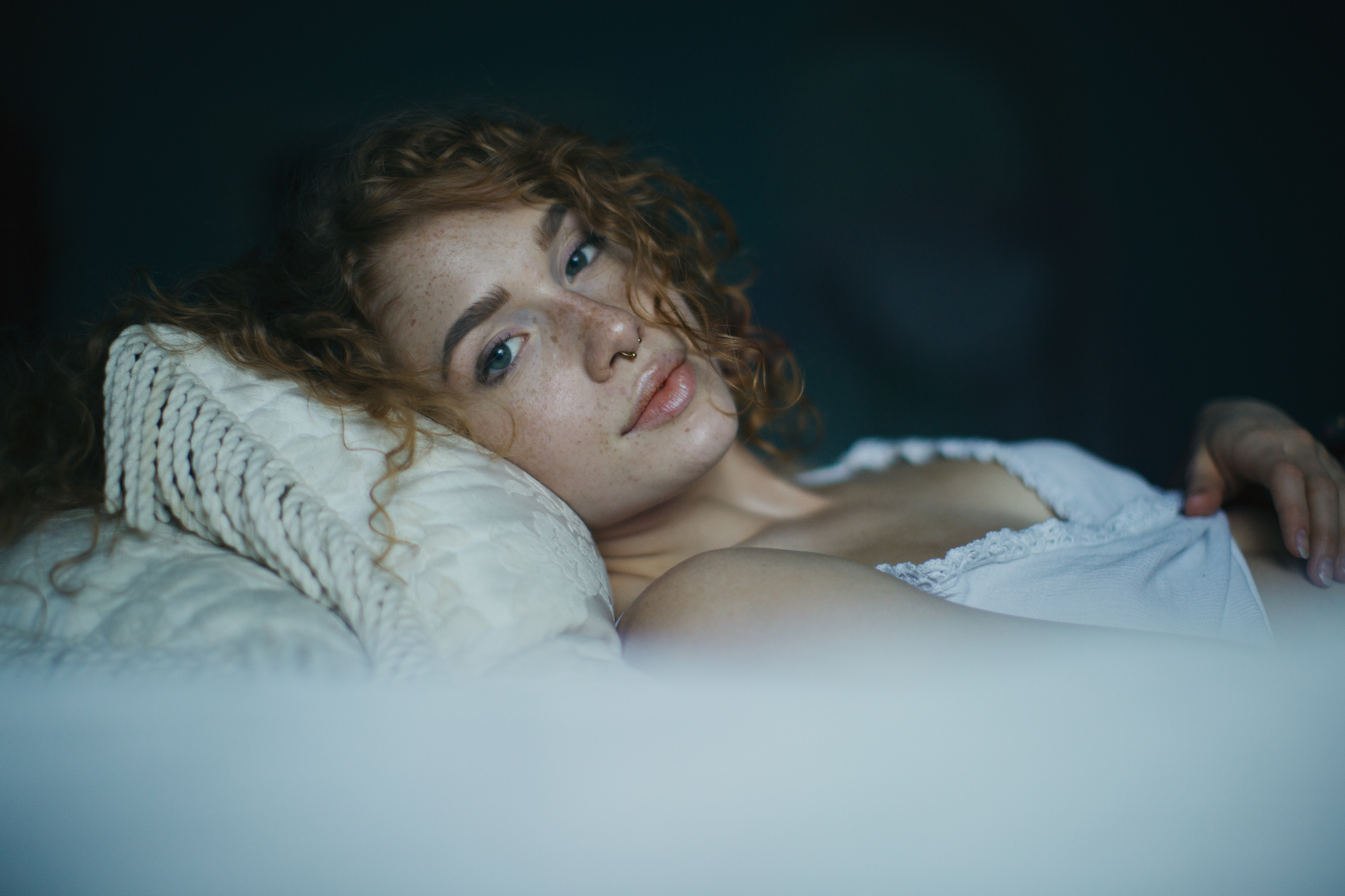 Woman with freckles lying on a pillow HD Wallpaper