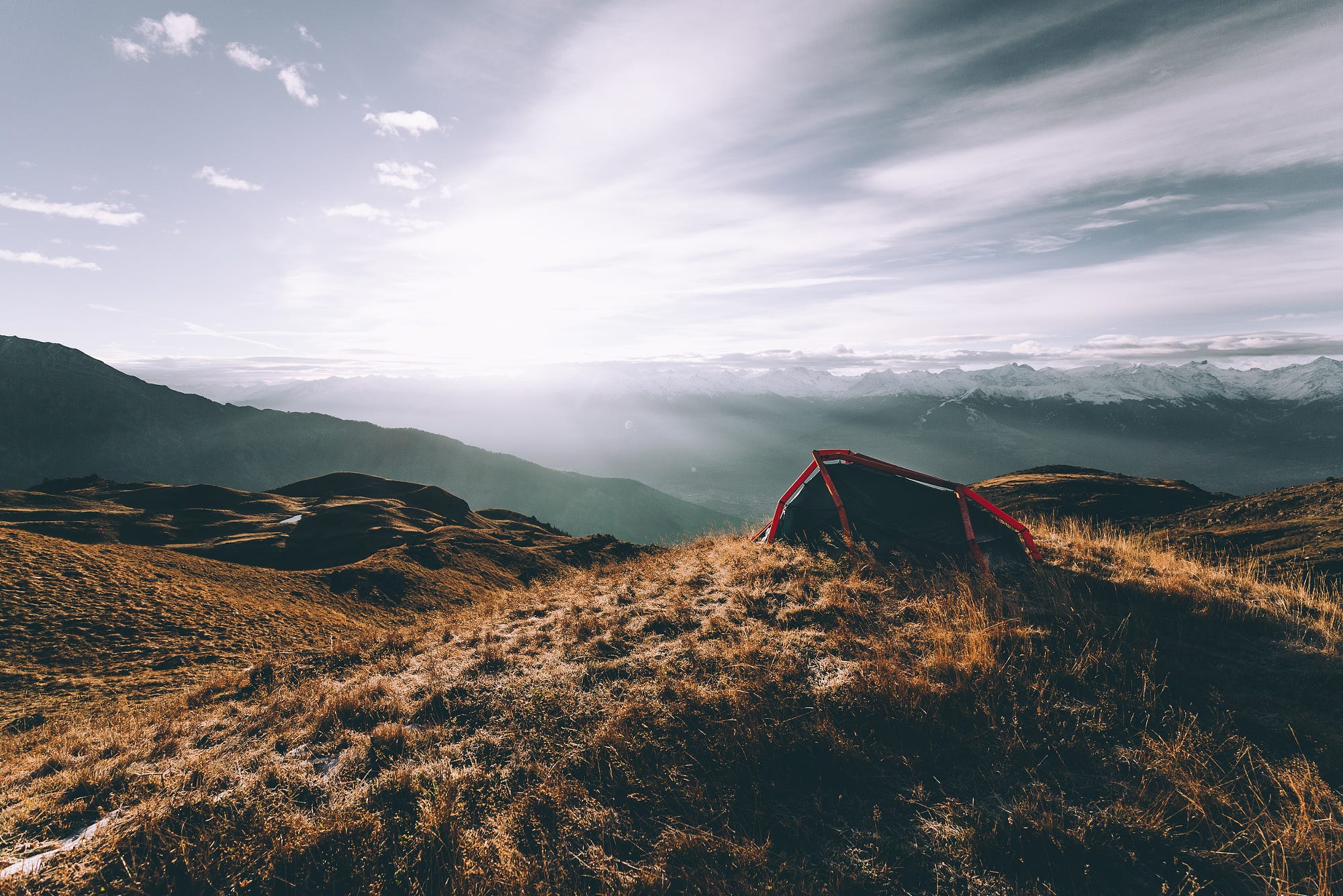 Tent on a grassy mountain ridge with sunlit clouds HD Wallpaper