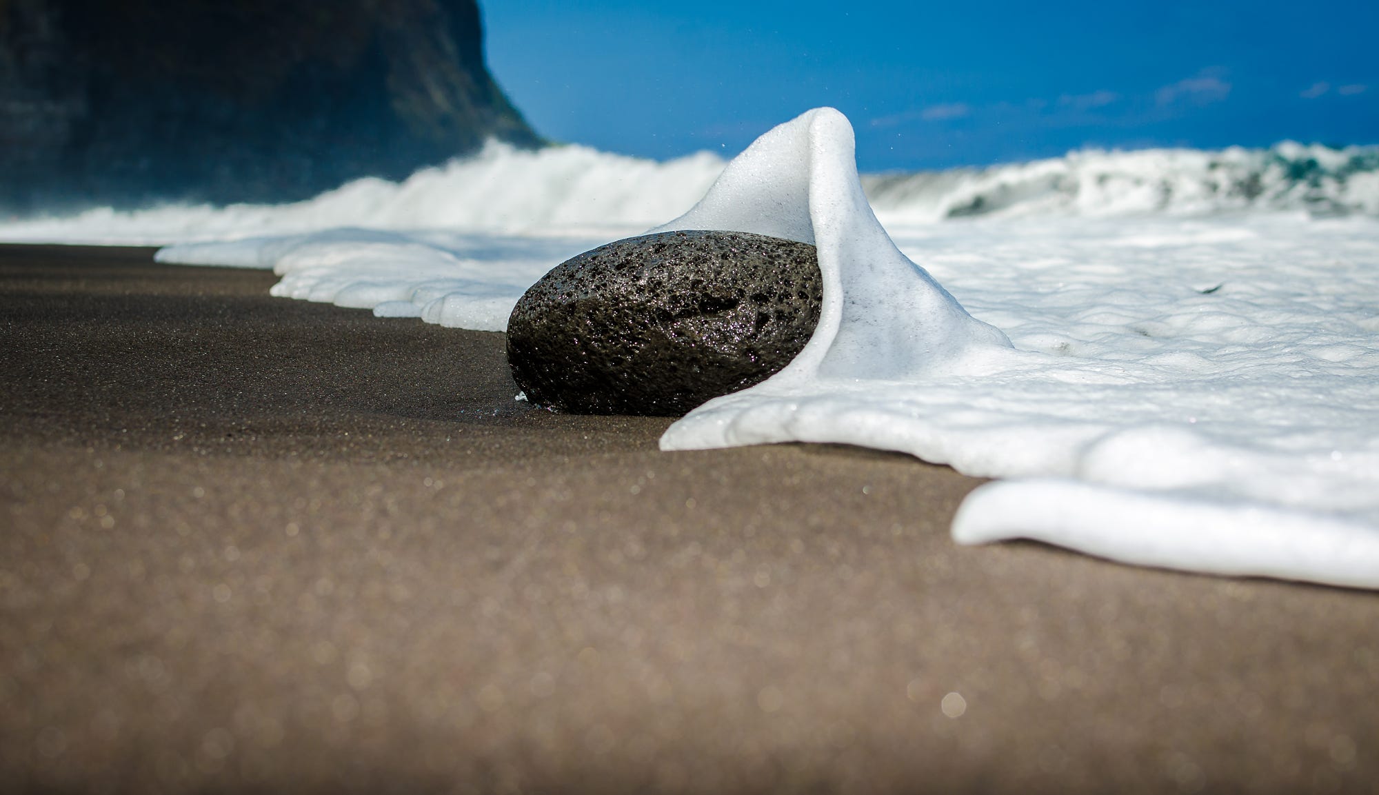 Black sand beach with waves and a rock HD Wallpaper