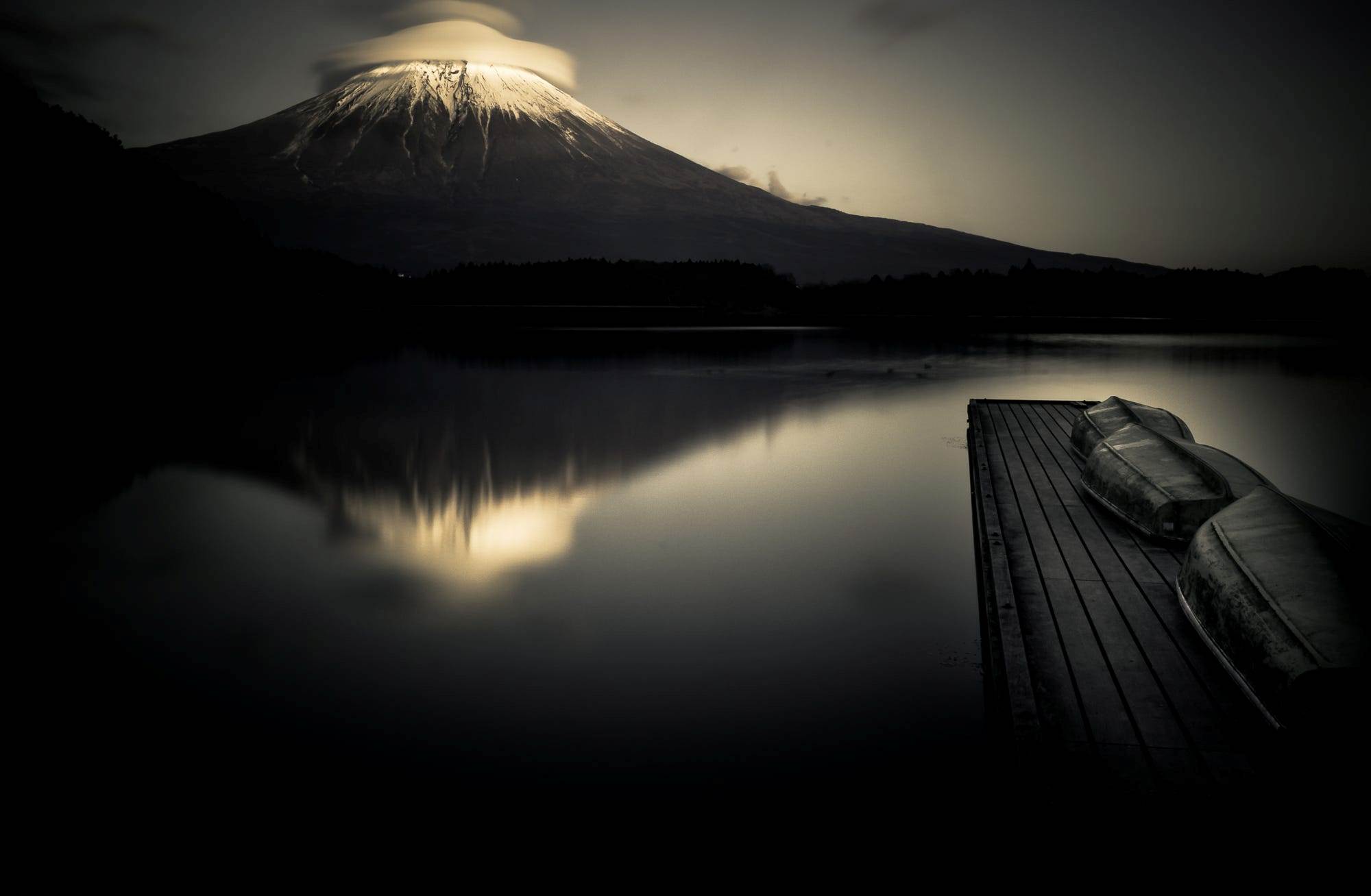 Mount Fuji reflected in a lake with boats on a dock HD Wallpaper