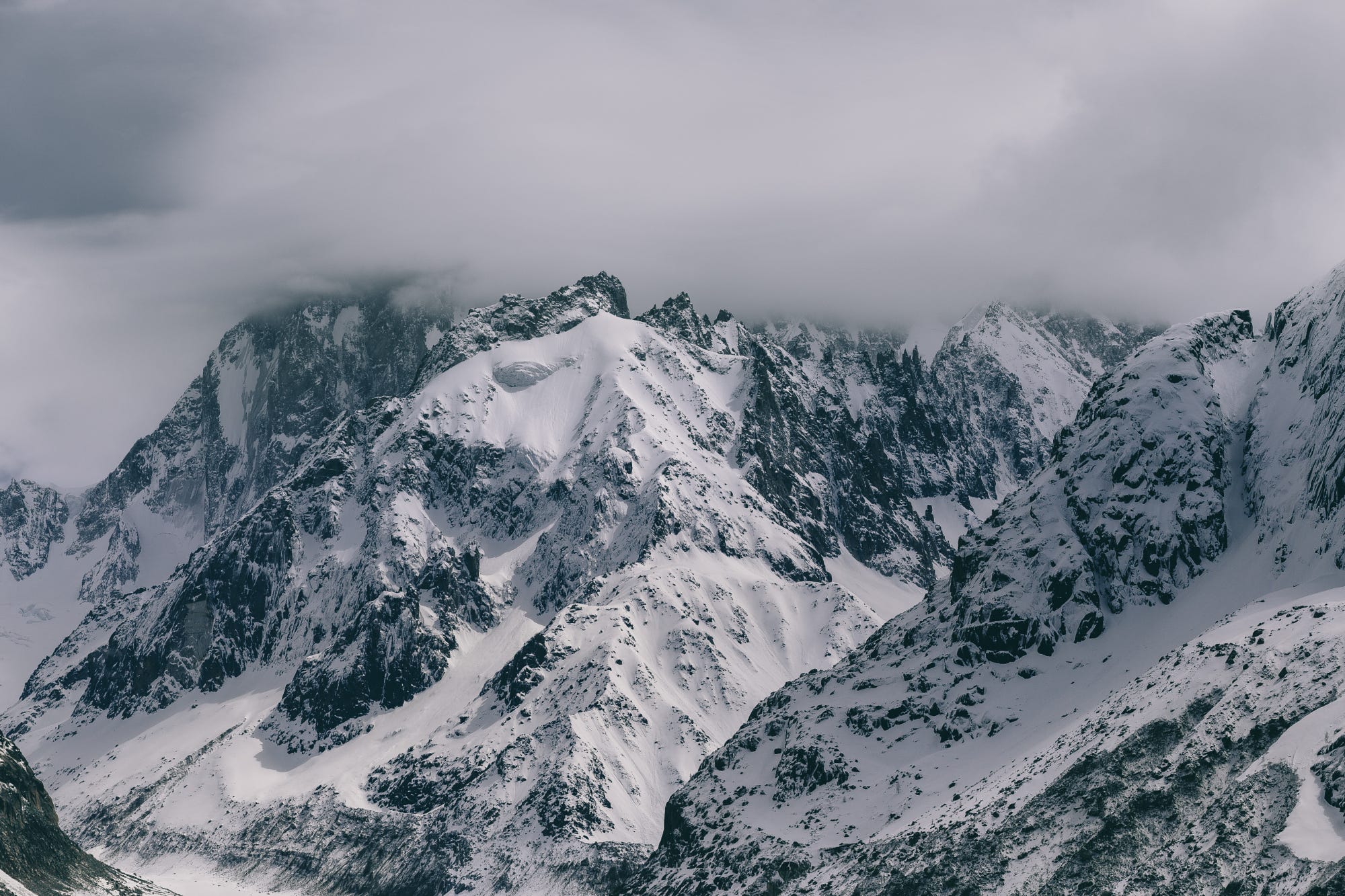 Snow-covered mountains under clouds in winter HD Wallpaper