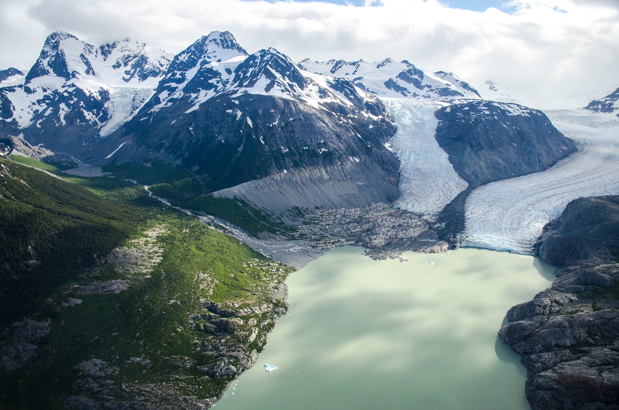 Glacier flowing into a lake with snow-capped mountains HD Wallpaper