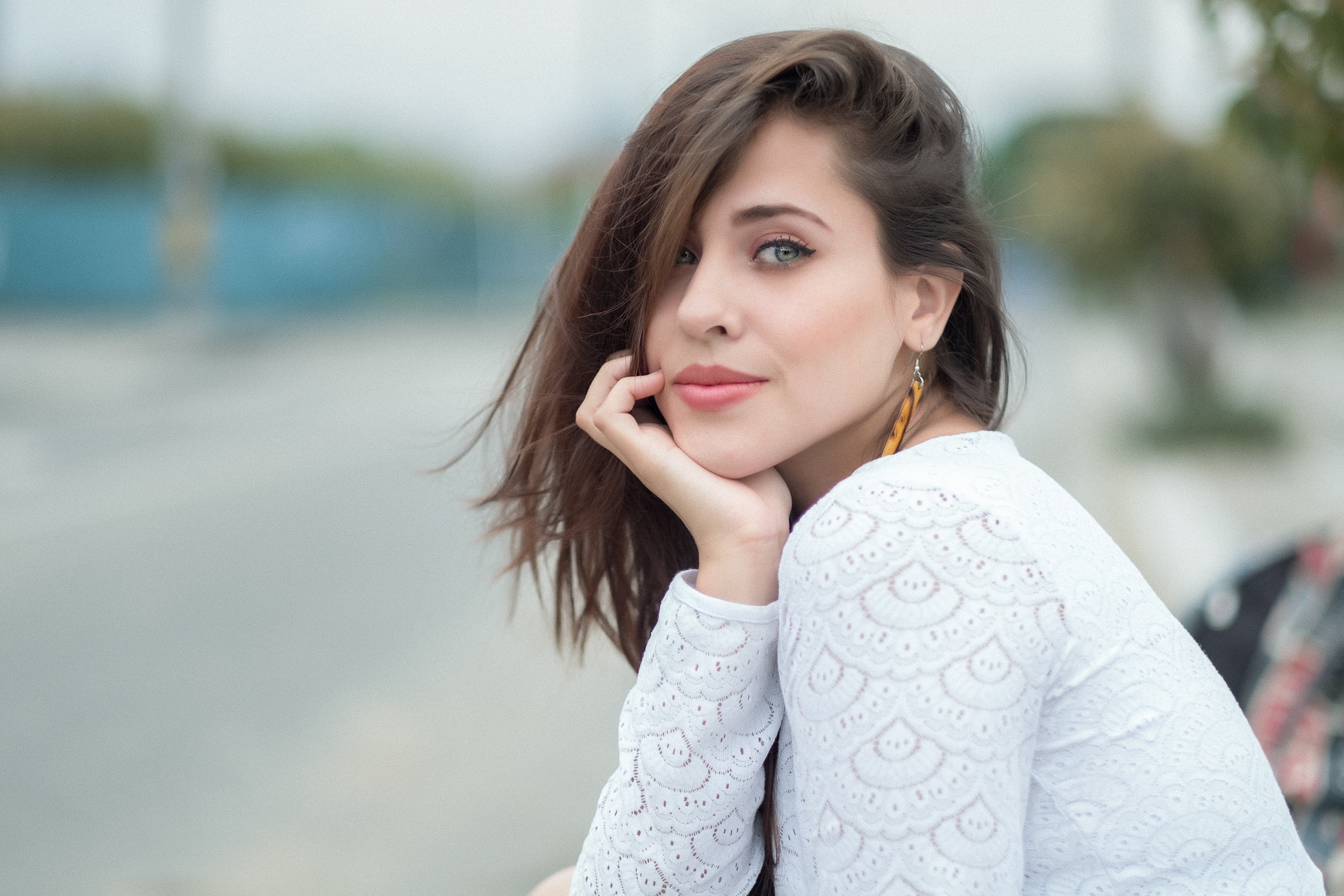 Woman with hand on chin, outdoor portrait HD Wallpaper