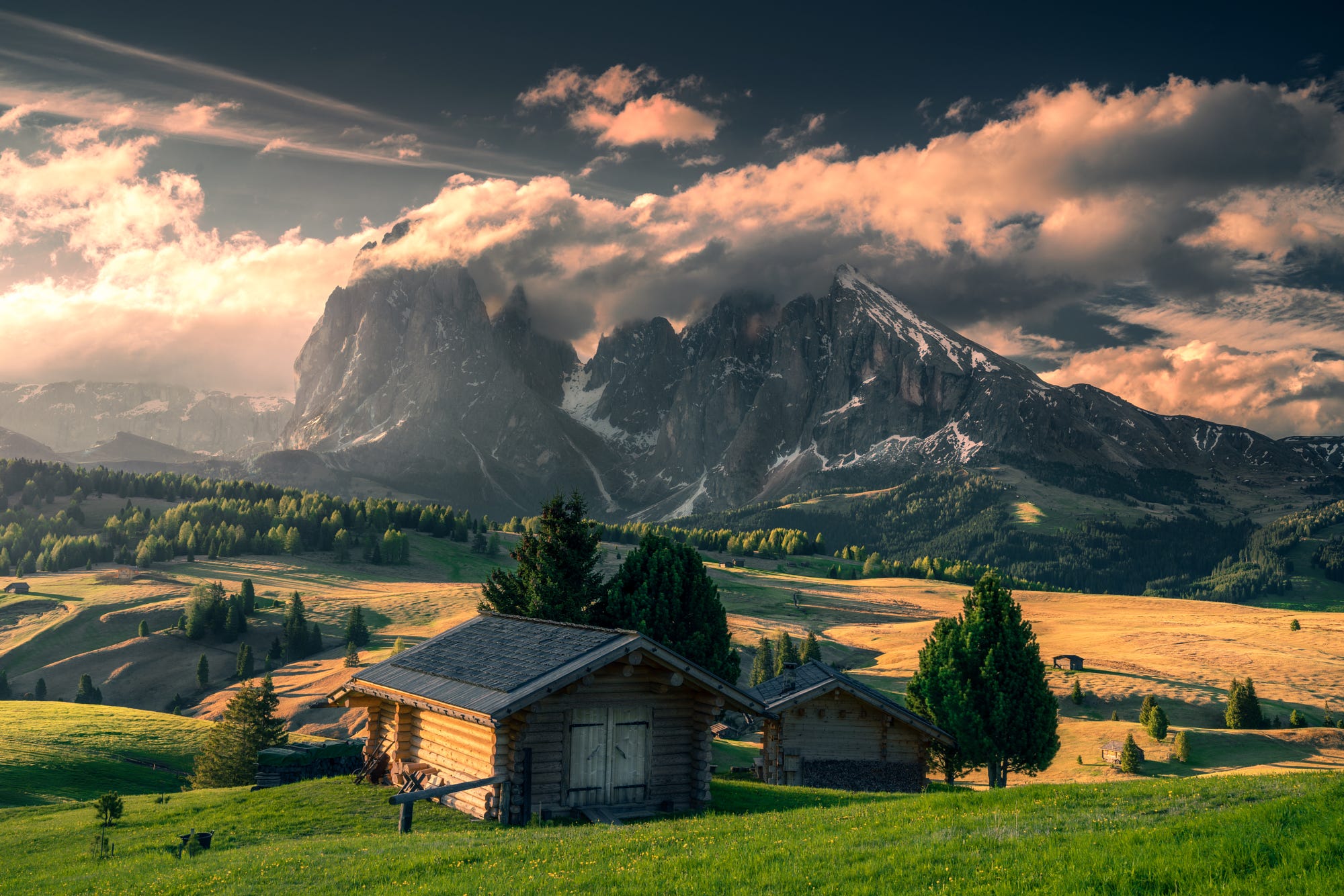 Wooden cabins in the Italian Alps with dramatic clouds HD Wallpaper