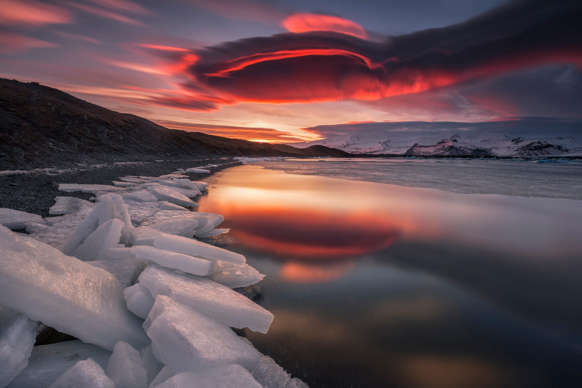 Ice chunks on a shore with a dramatic sunset reflection HD Wallpaper