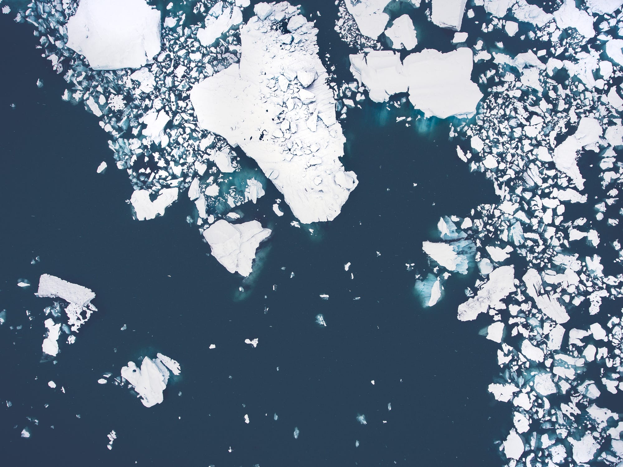 Aerial view of icebergs floating in dark water HD Wallpaper
