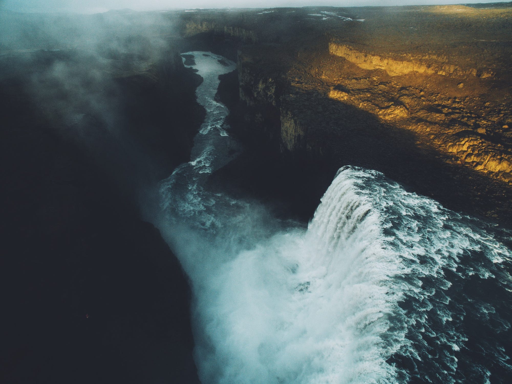 Waterfall cascading into a canyon with mist HD Wallpaper