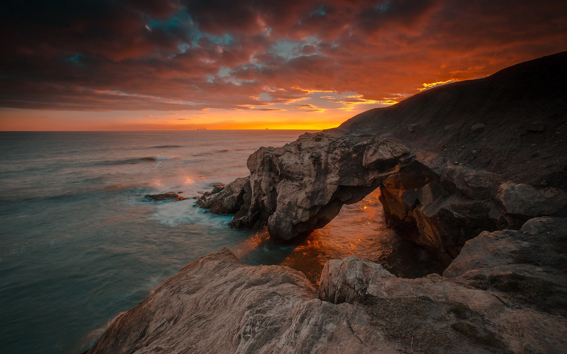 Sunset over rocky coast with natural arch HD Wallpaper