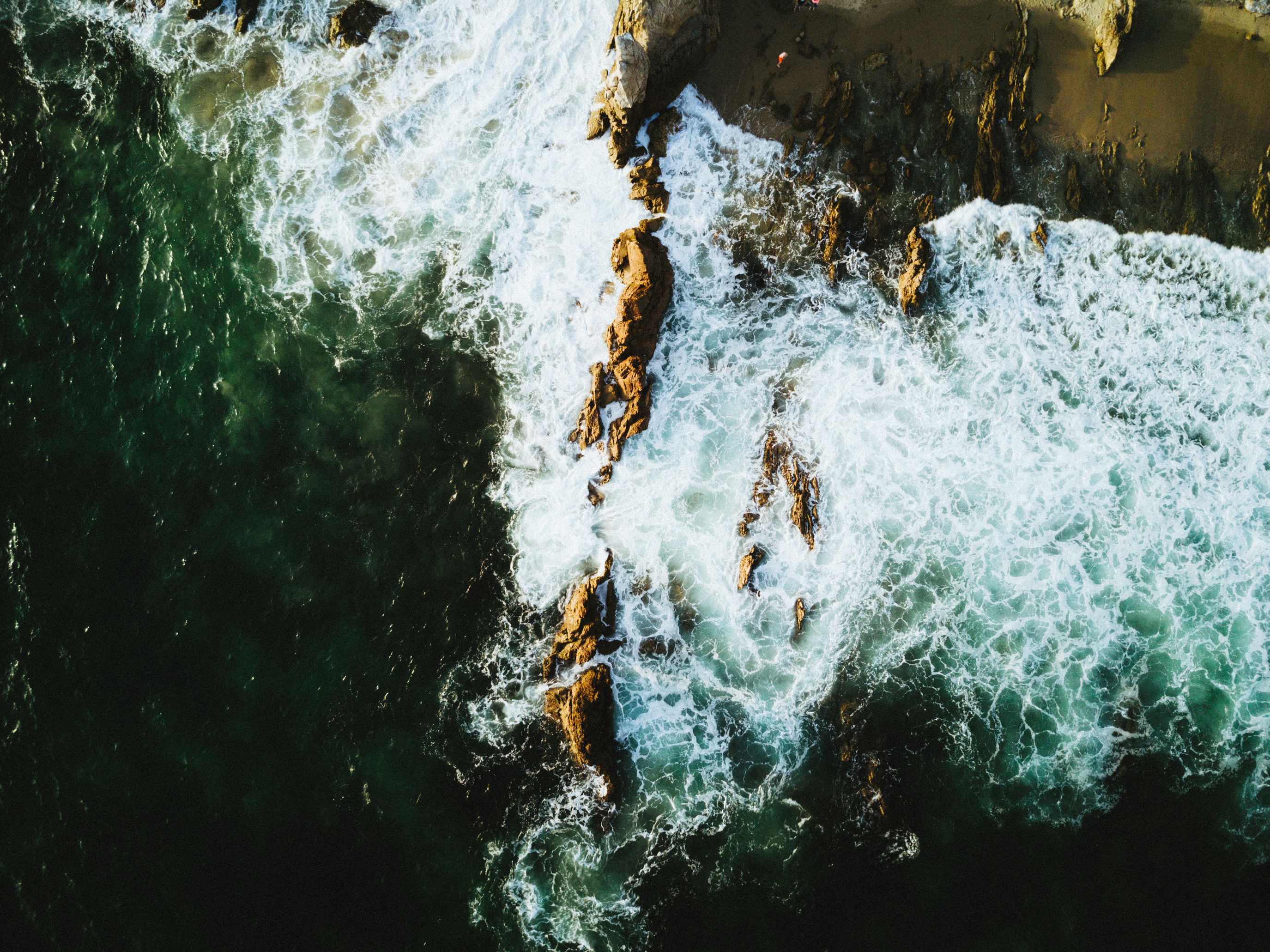 Aerial view of ocean waves crashing on rocky shore HD Wallpaper