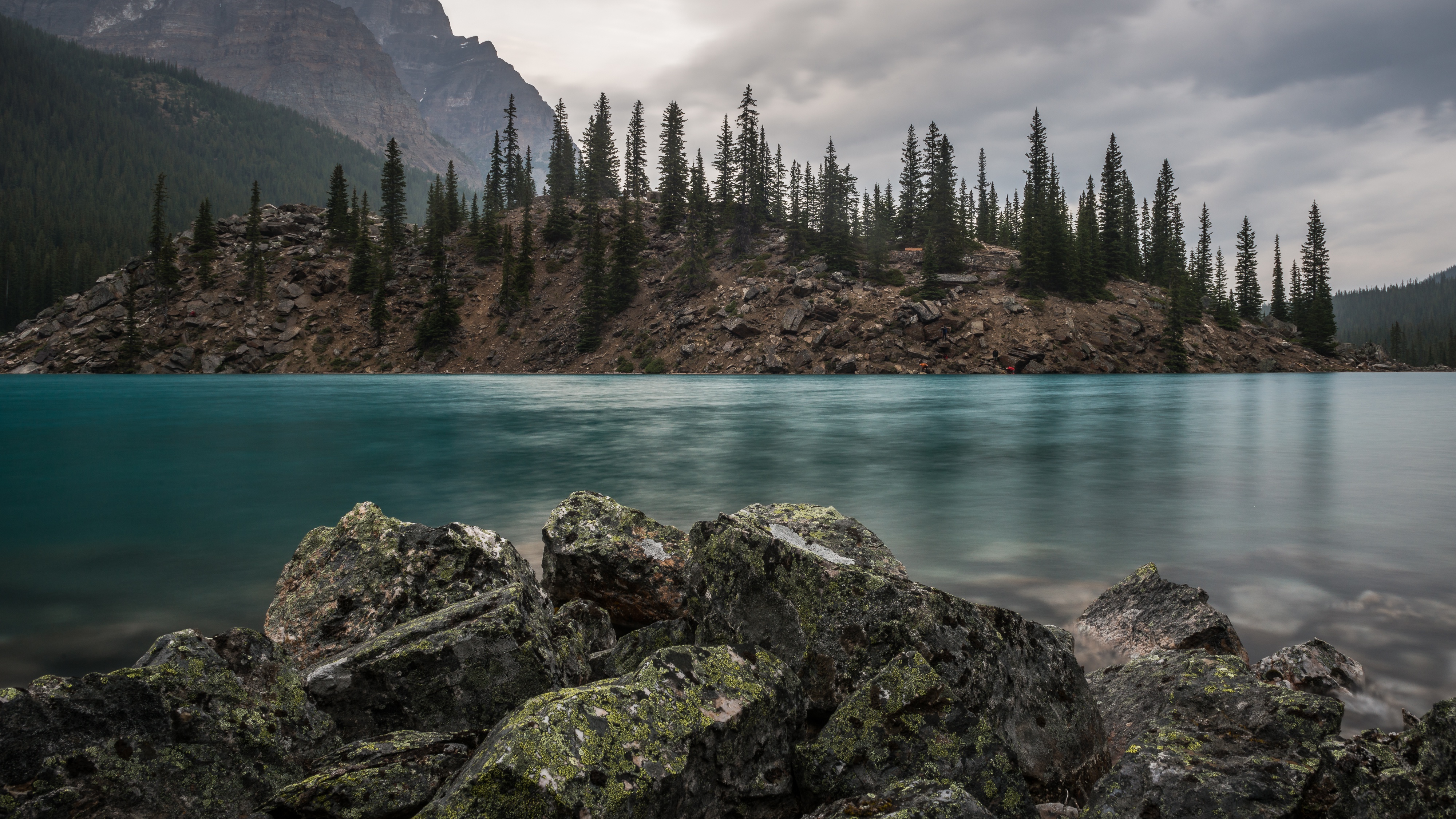 Turquoise lake with rocky shore and pine trees HD Wallpaper