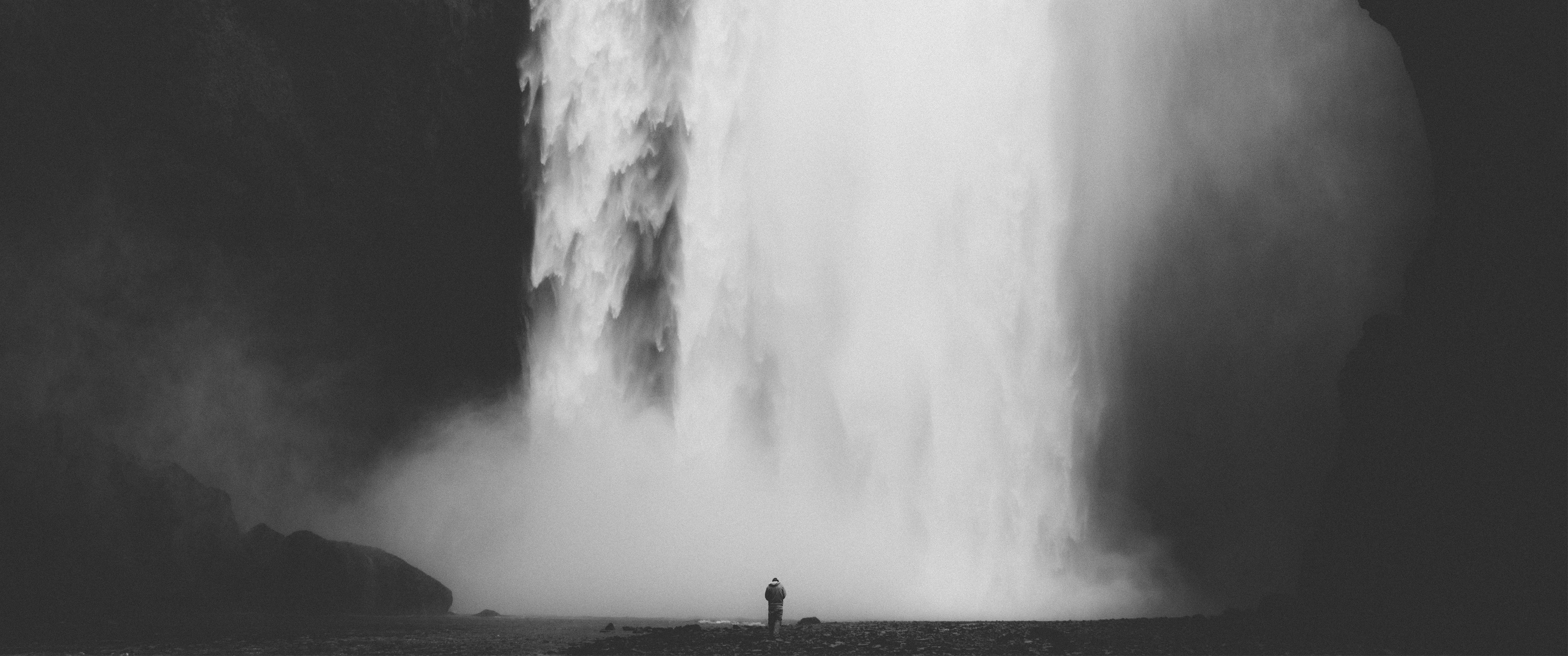 Monochrome waterfall with a lone person standing HD Wallpaper