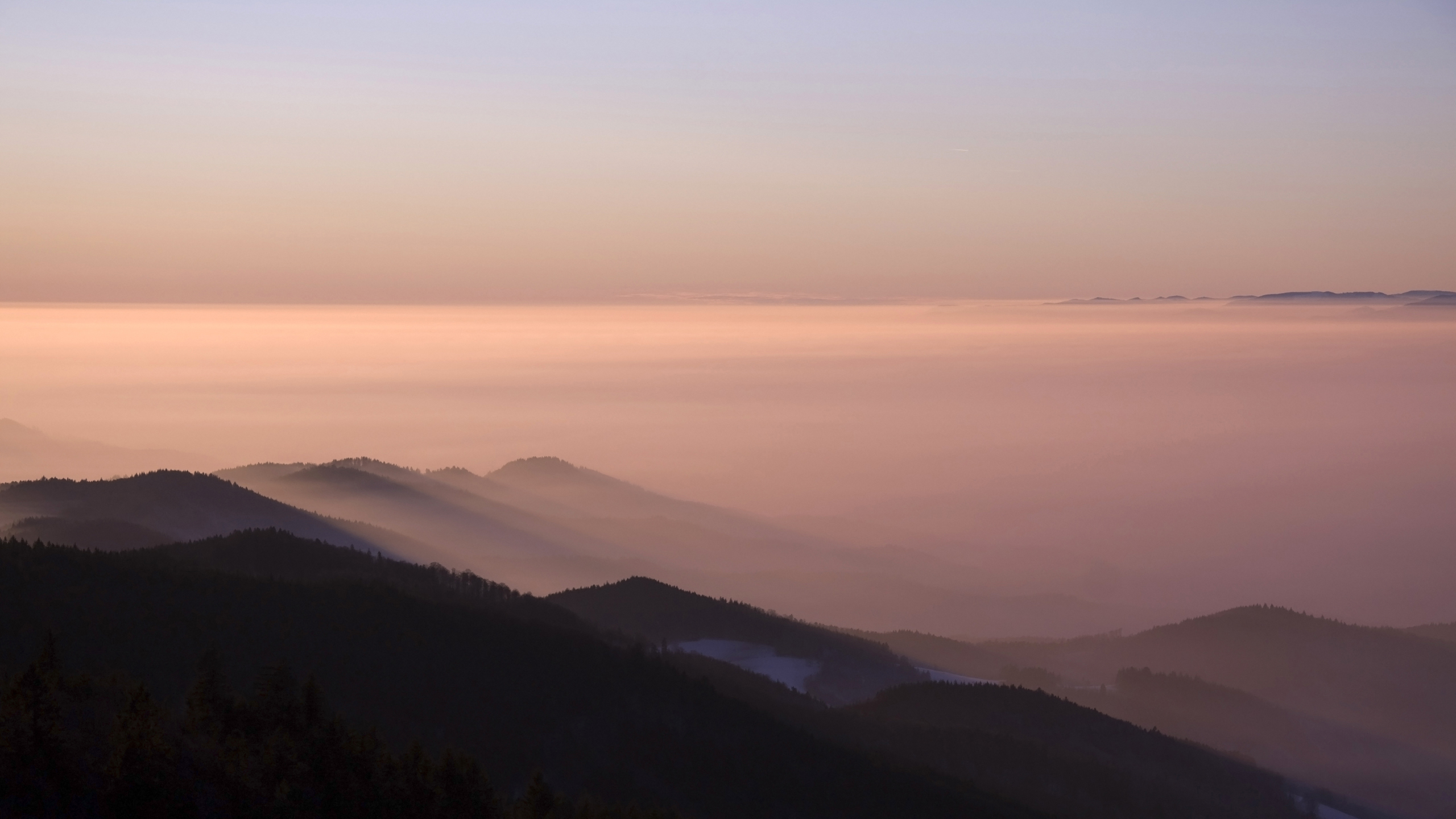Mountain range shrouded in mist at sunrise HD Wallpaper