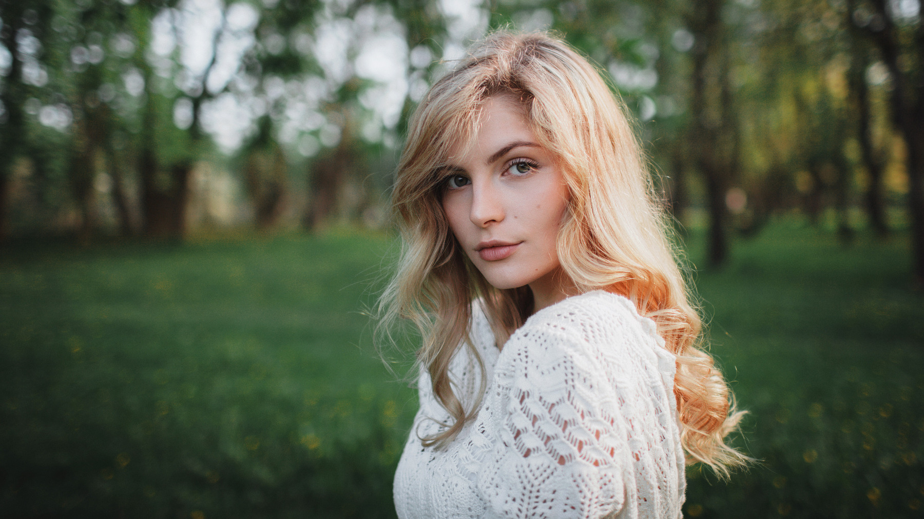 Woman with blonde hair in a white sweater outdoors HD Wallpaper