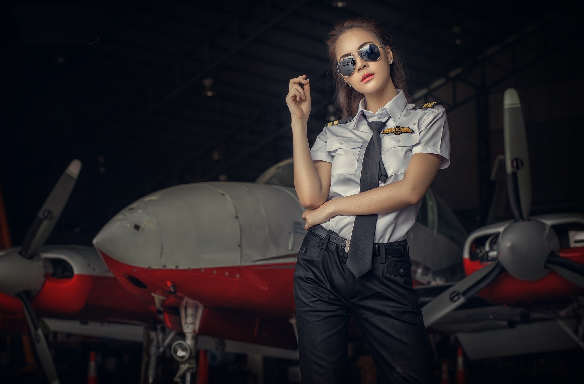 Woman pilot in uniform posing in hangar with airplane HD Wallpaper