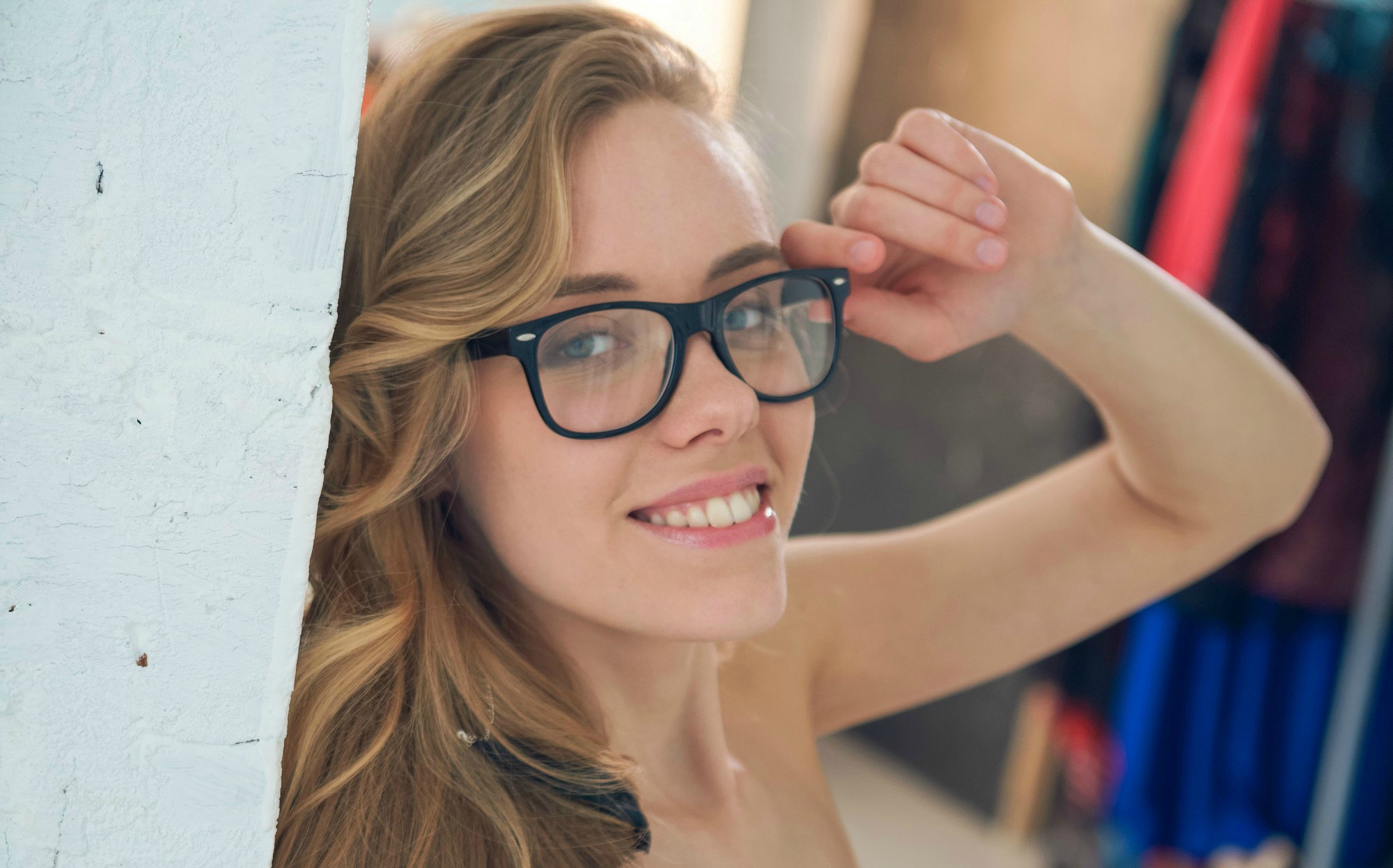 Woman with glasses leaning against a wall HD Wallpaper