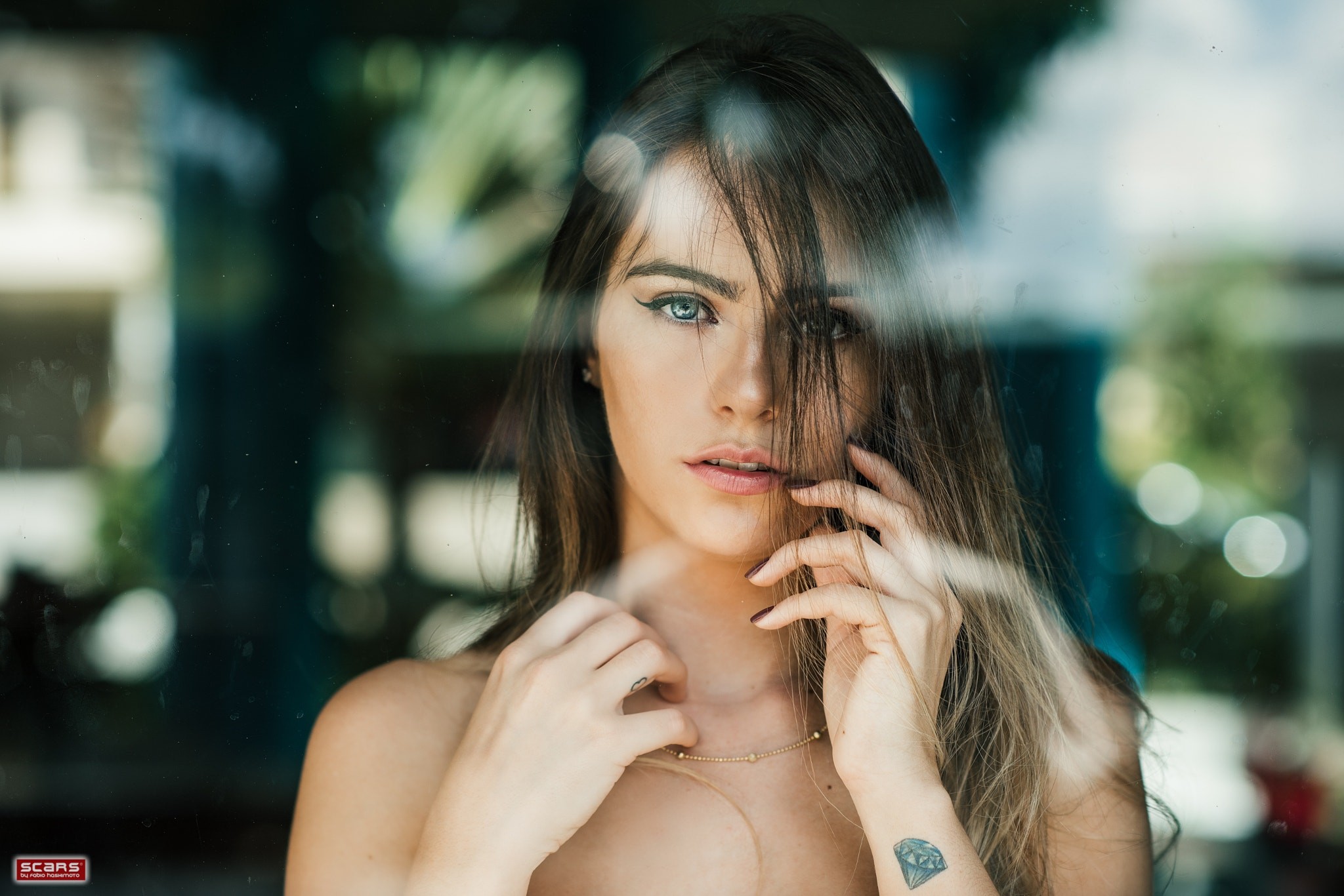 Woman with blue eyes and tattoos behind glass HD Wallpaper