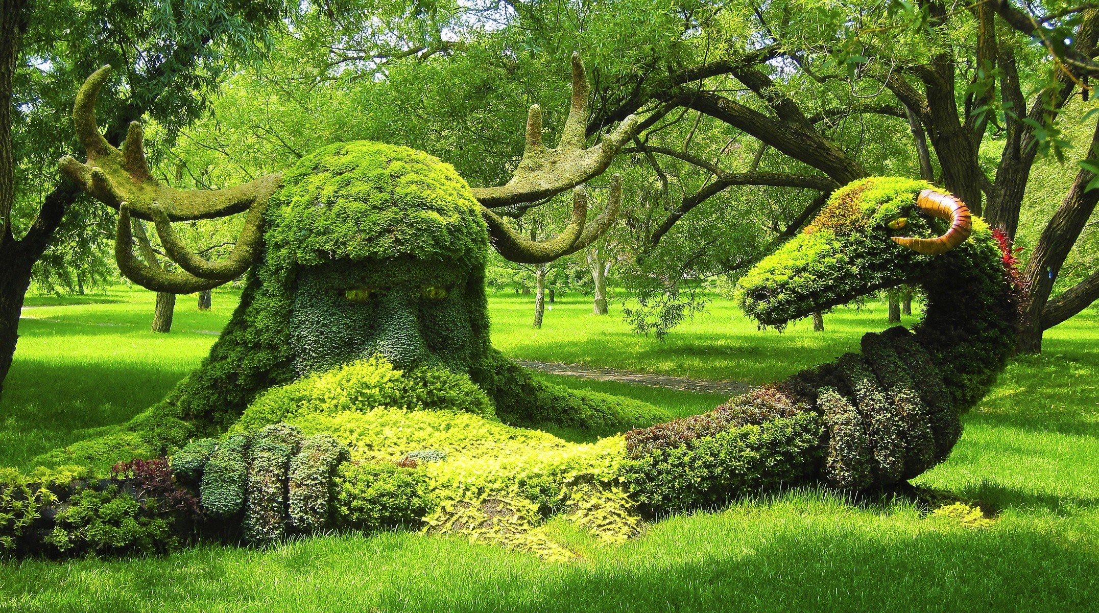 Moss sculptures of a giant and a dragon in a park HD Wallpaper