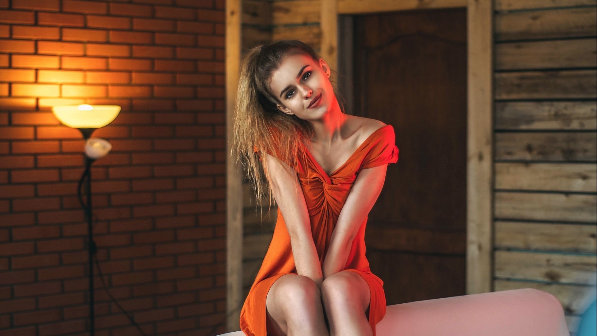 Woman in orange dress sitting indoors HD Wallpaper