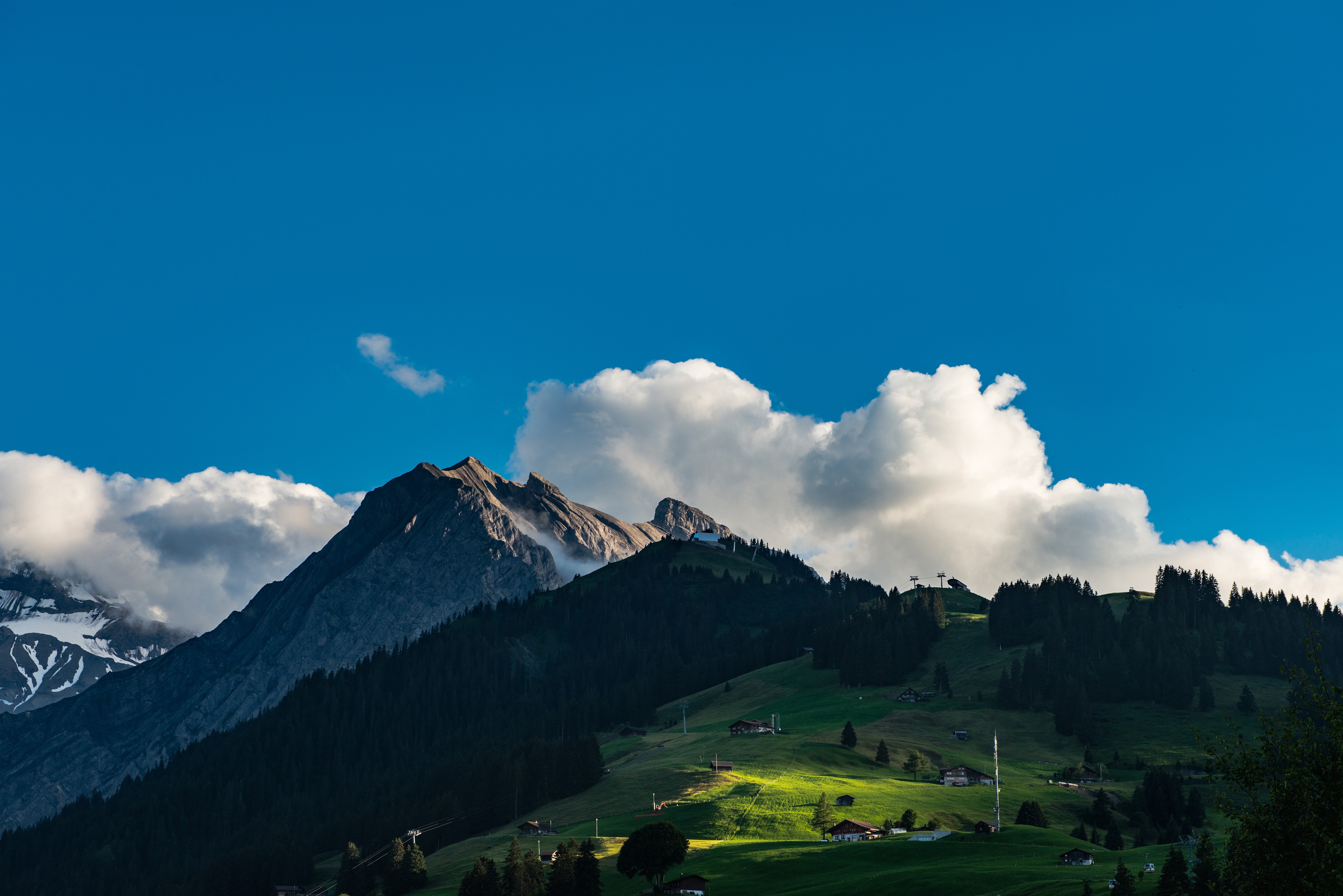 Mountains and clouds over a green landscape in Switzerland HD Wallpaper