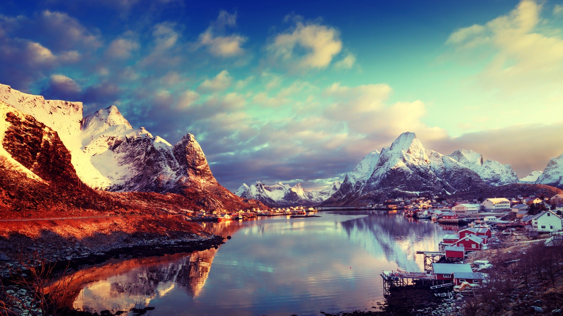 Snowy mountains and village reflected in water in Lofoten, Norway HD Wallpaper