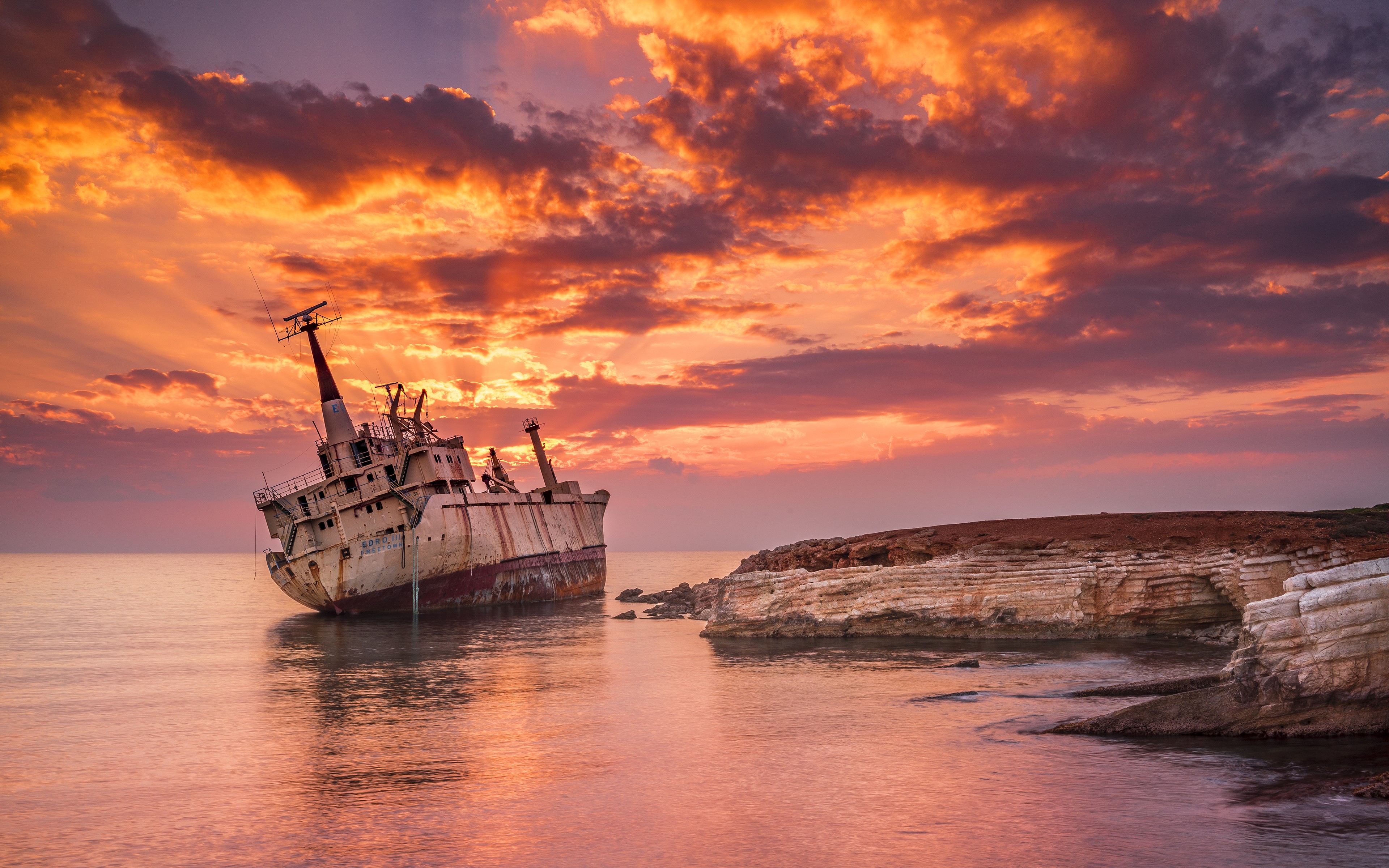 Shipwreck on the coast during a dramatic sunset HD Wallpaper